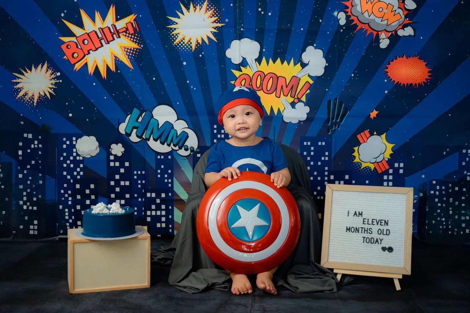 Superhero themed photo setup with comic book style backdrop and Captain America props.