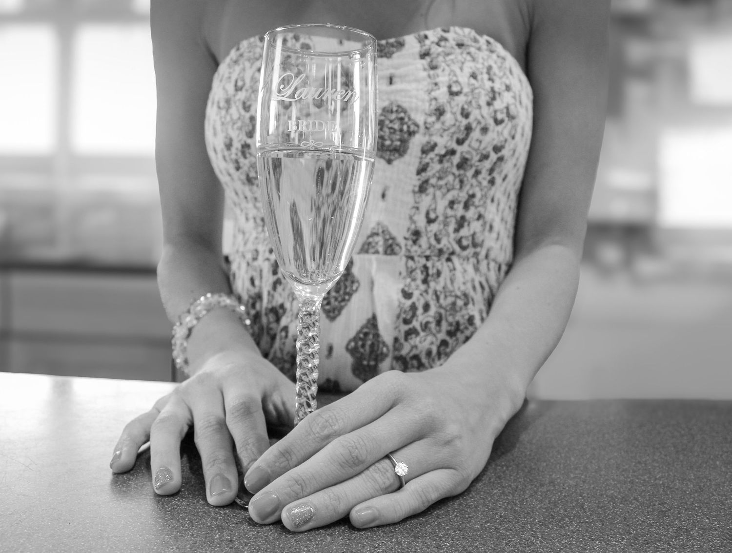 Black and white engagement photo of a woman holding a champagne glass, showing her engagement ring in Fairfield County.