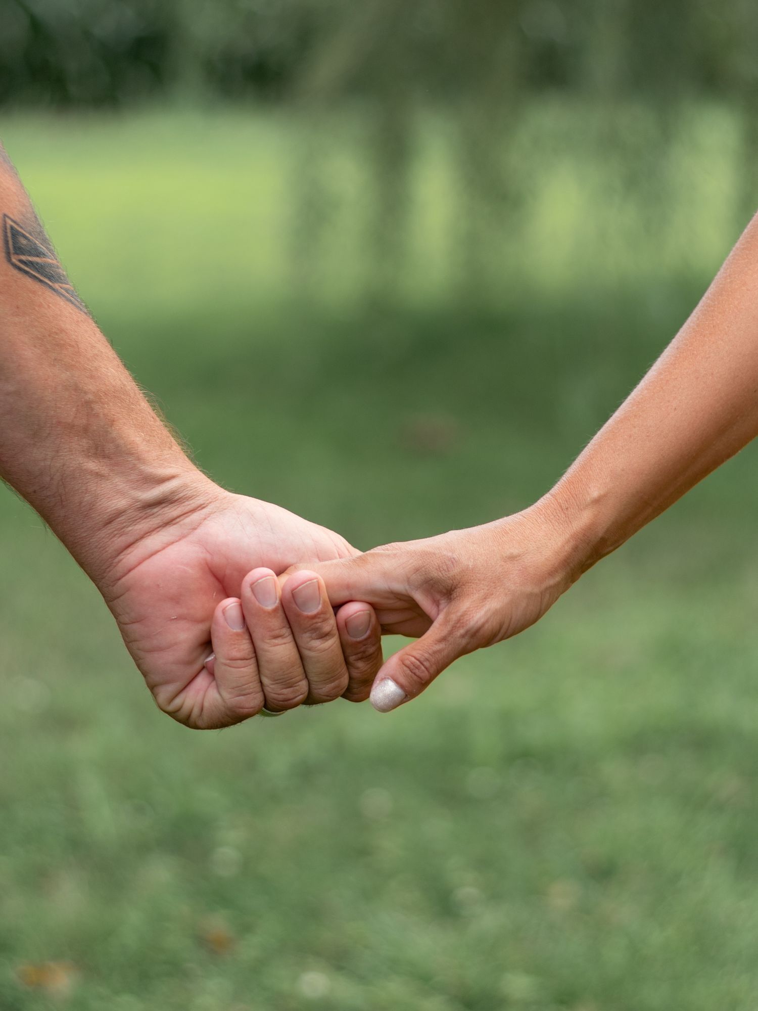 Close-up sequence of two hands reaching out and holding each other outdoors.