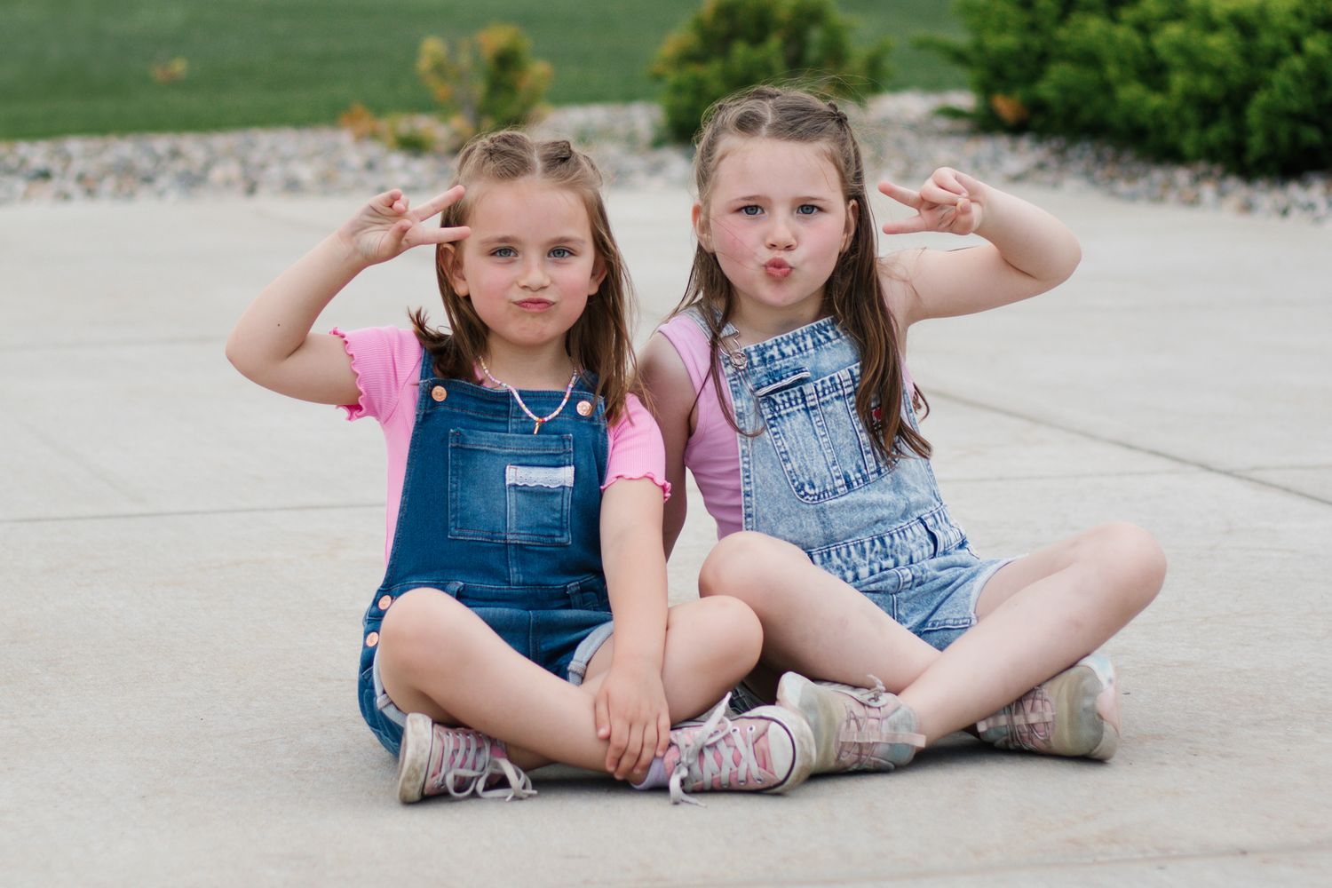 Children in casual summer clothes sitting and playing on pavement.