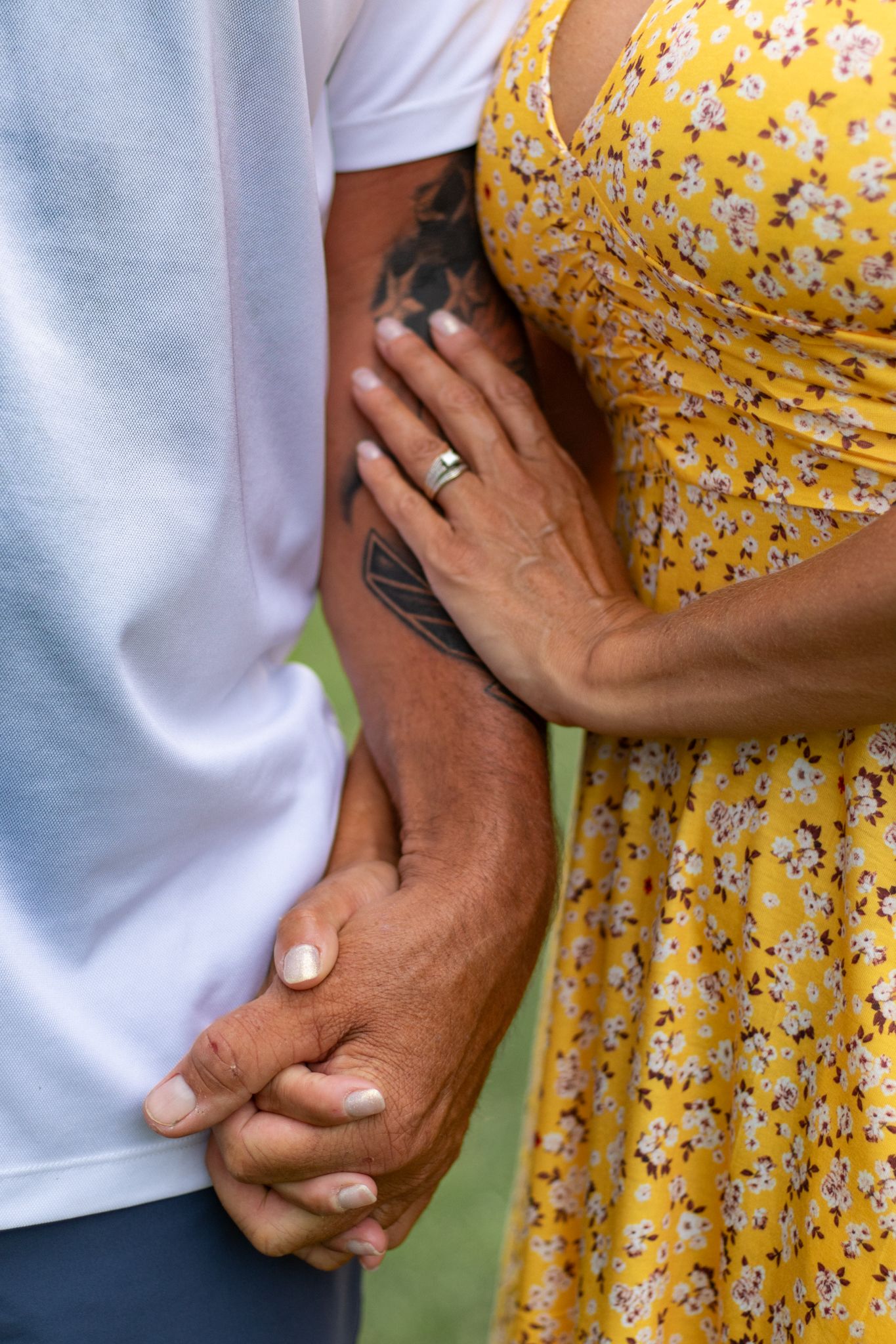 Detail shots of hands touching and embracing against yellow floral dress and white shirt backgrounds.