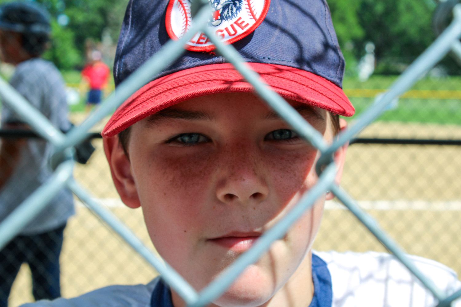 Baseball player wearing red cap and uniform during practice on diamond field.
