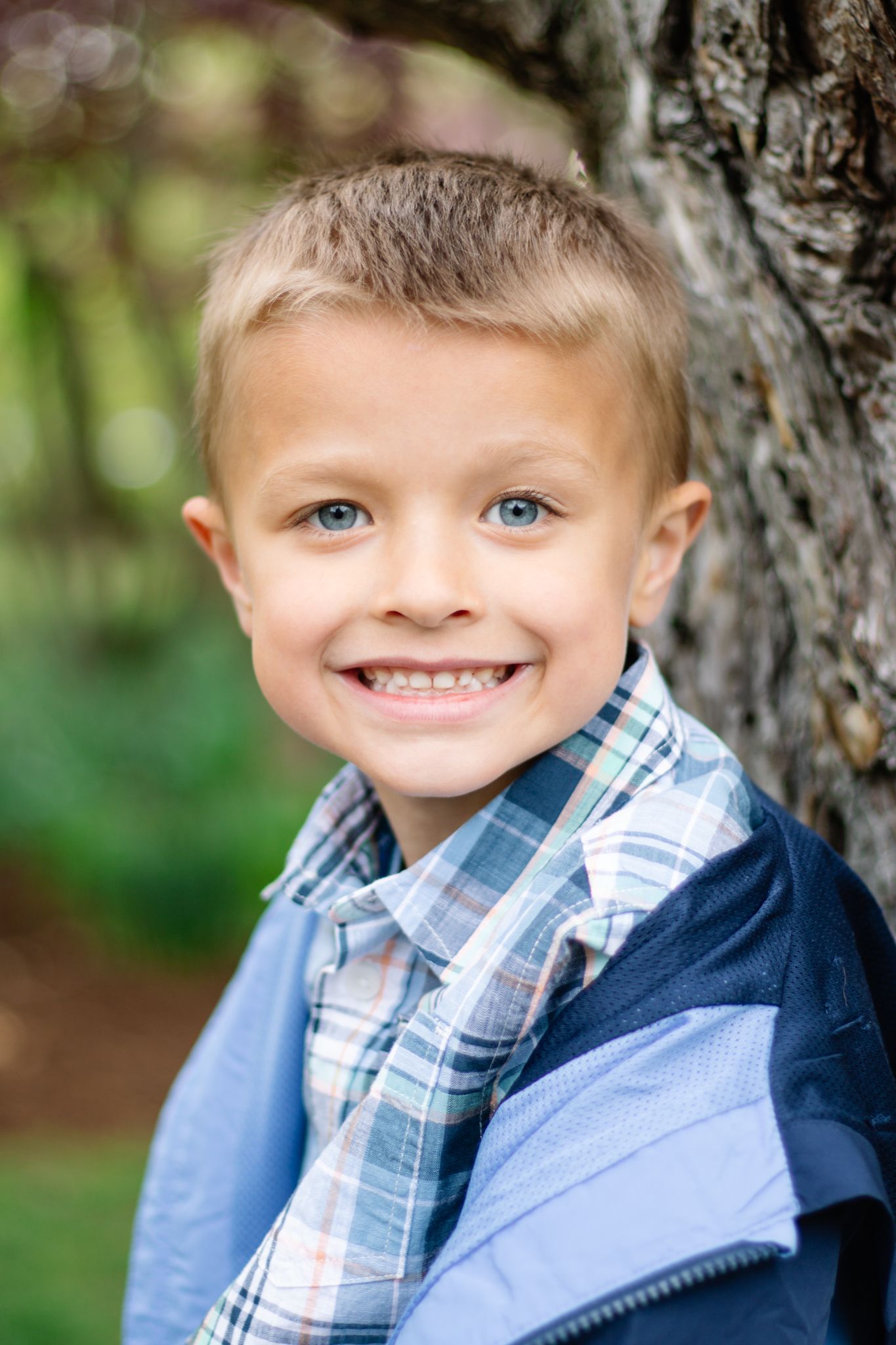 Series of close-up expressions wearing plaid shirt and navy jacket against tree bark.