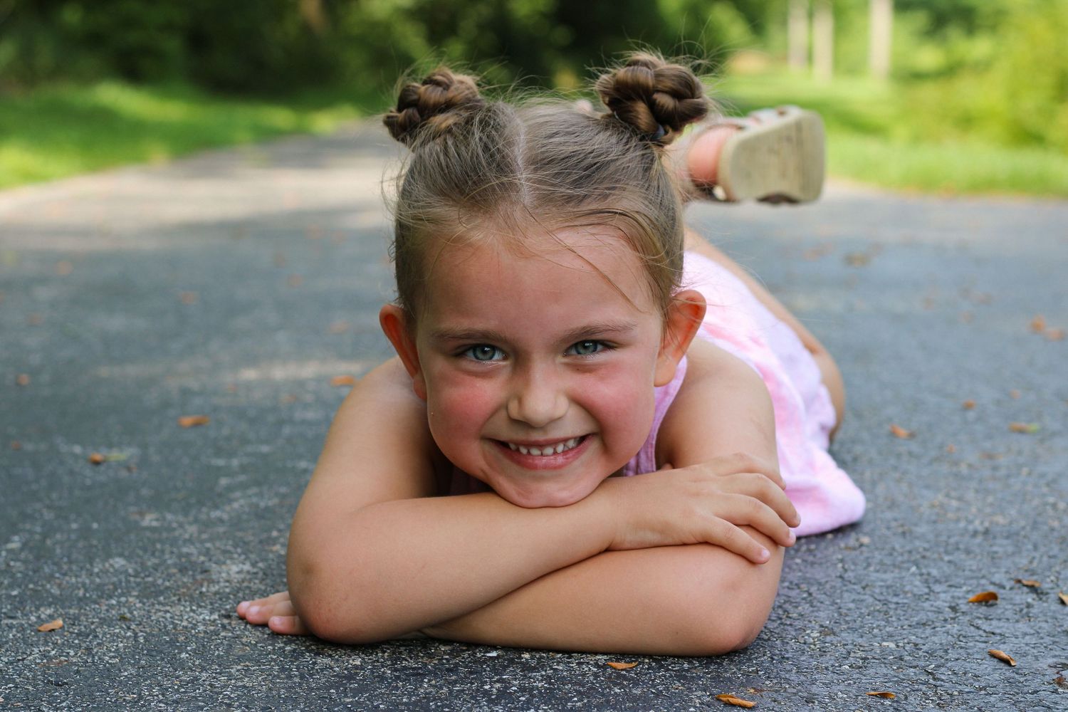 Child lying relaxed on pavement during outdoor summer photo session.