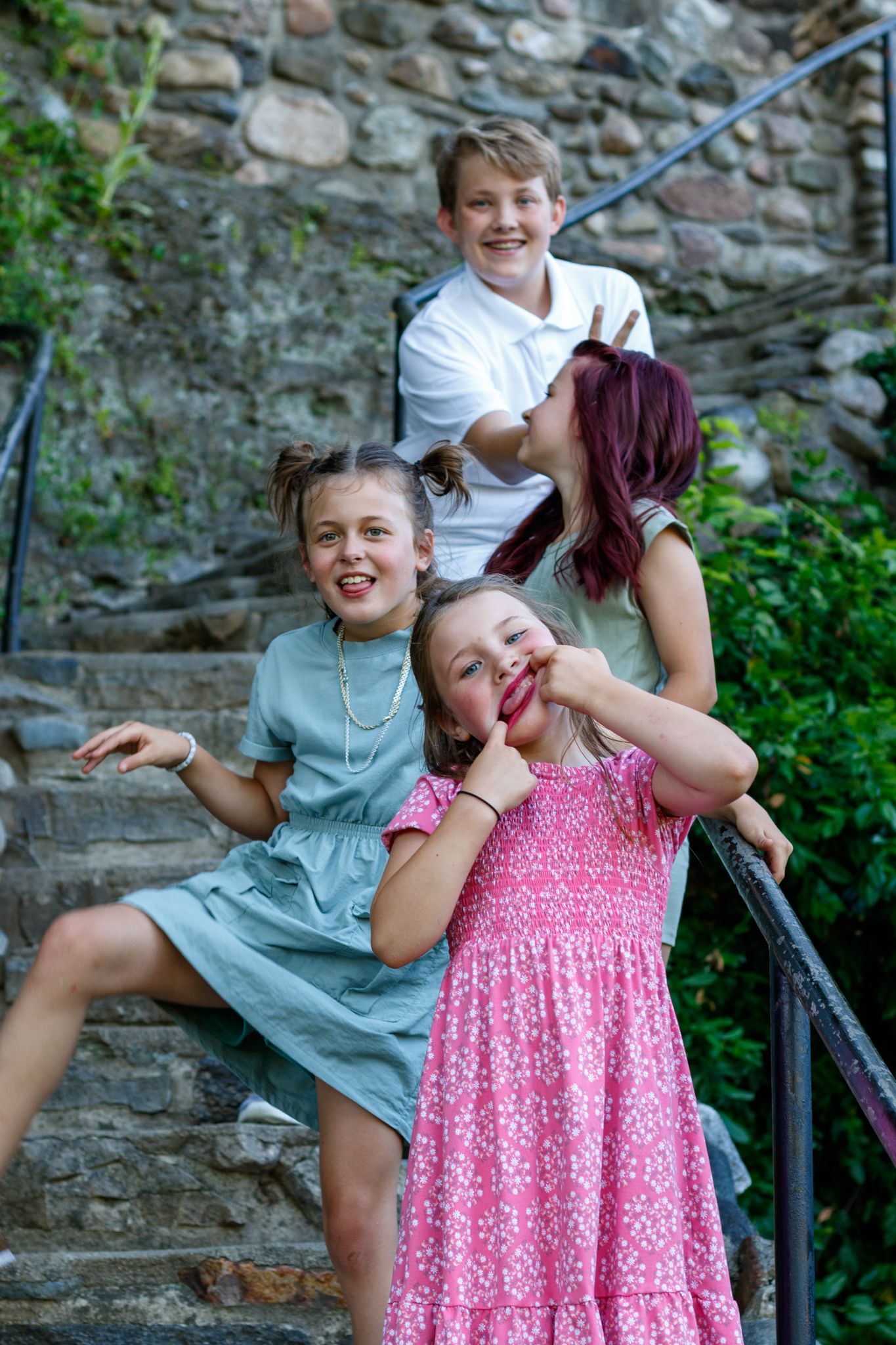 Candid and playful moments captured of family members on stone steps in a garden setting.