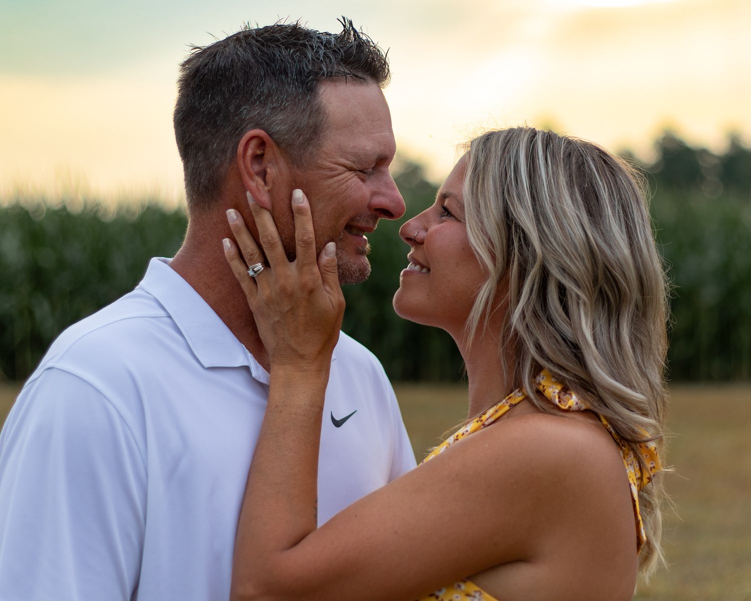 Romantic sunset photoshoot with couple in white clothing in golden field.