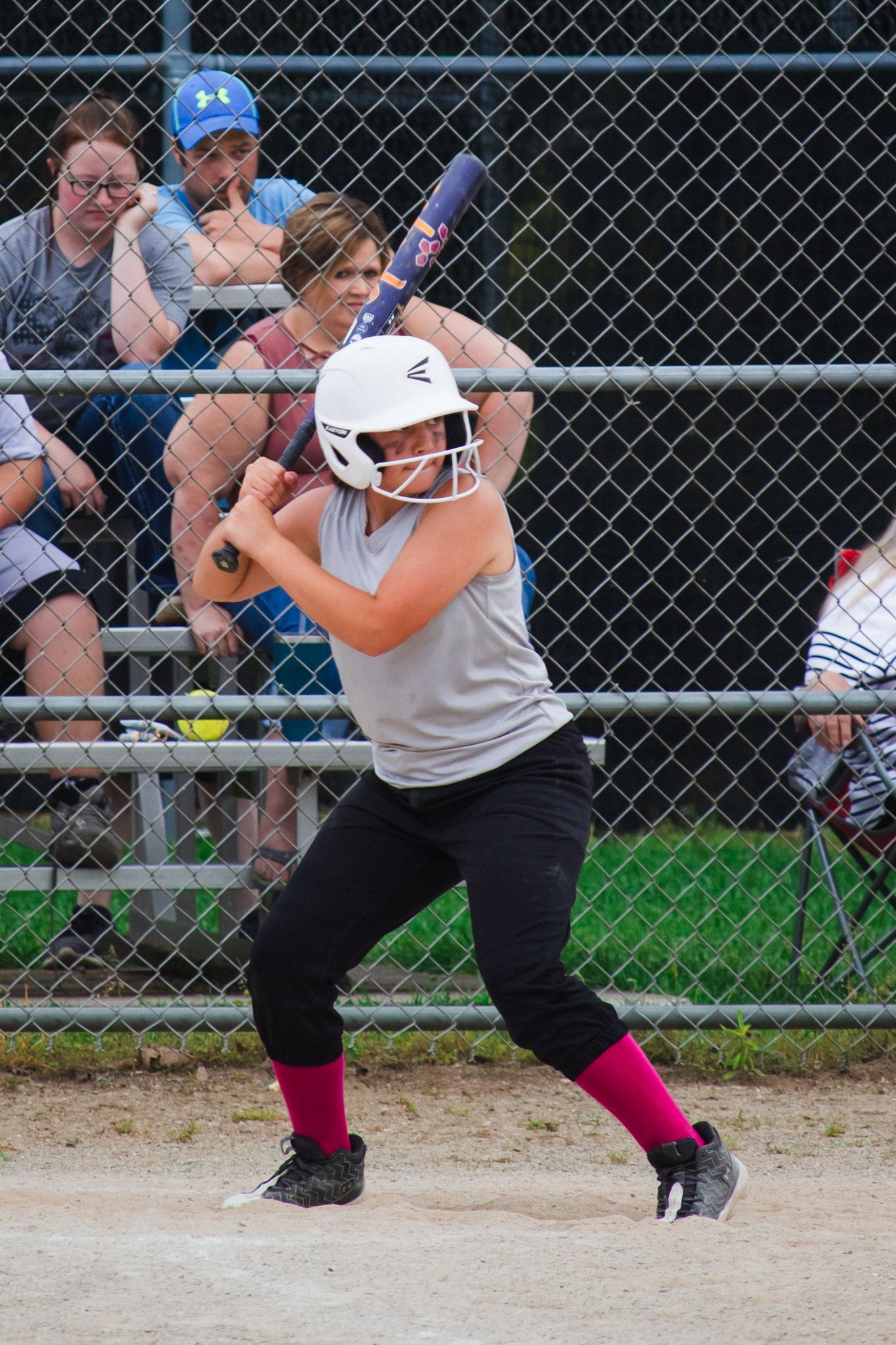 Side view of softball player in batting stance preparing to hit during game.