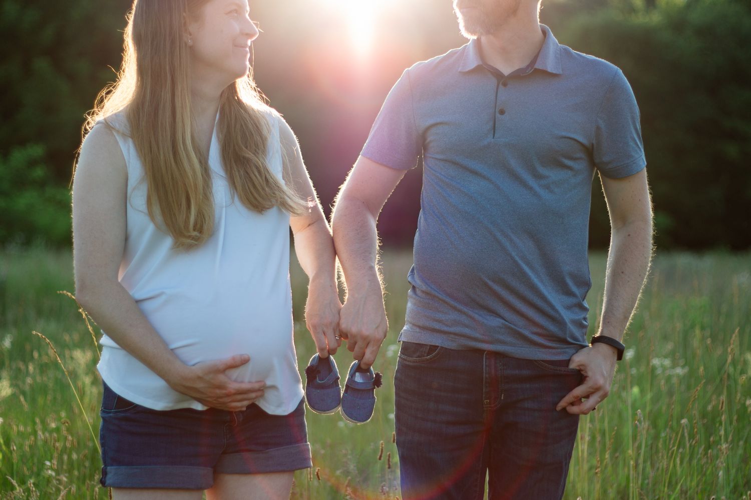 A tender moment between expecting parents in golden hour lighting.