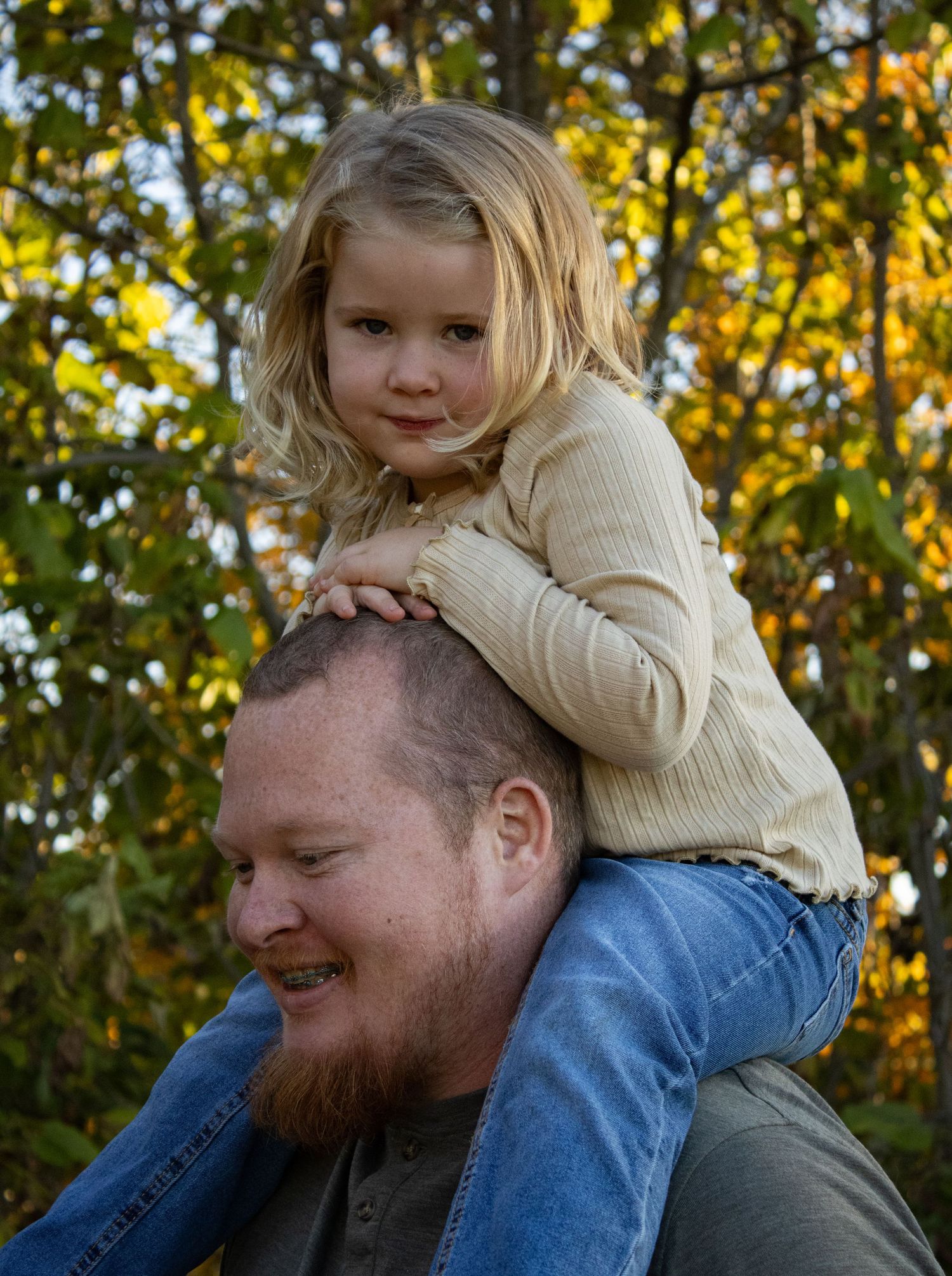 Playful outdoor family moment captured with autumn trees in the background.
