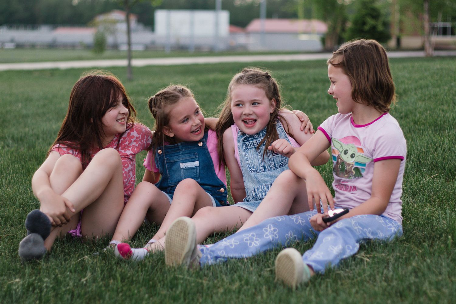 Friends relaxing together on grass during outdoor photoshoot.
