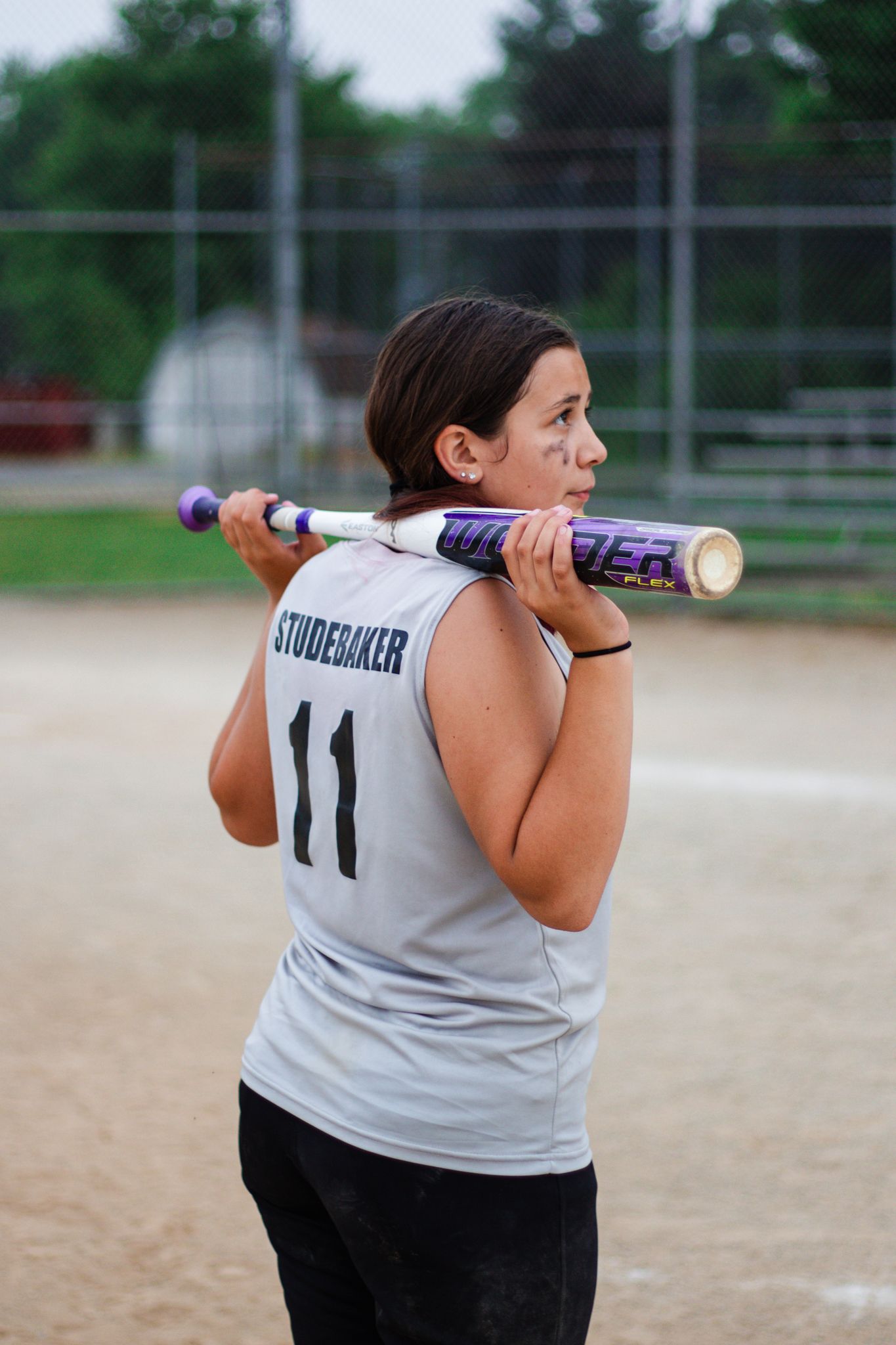 Side view of softball player with jersey number 11 preparing to bat.