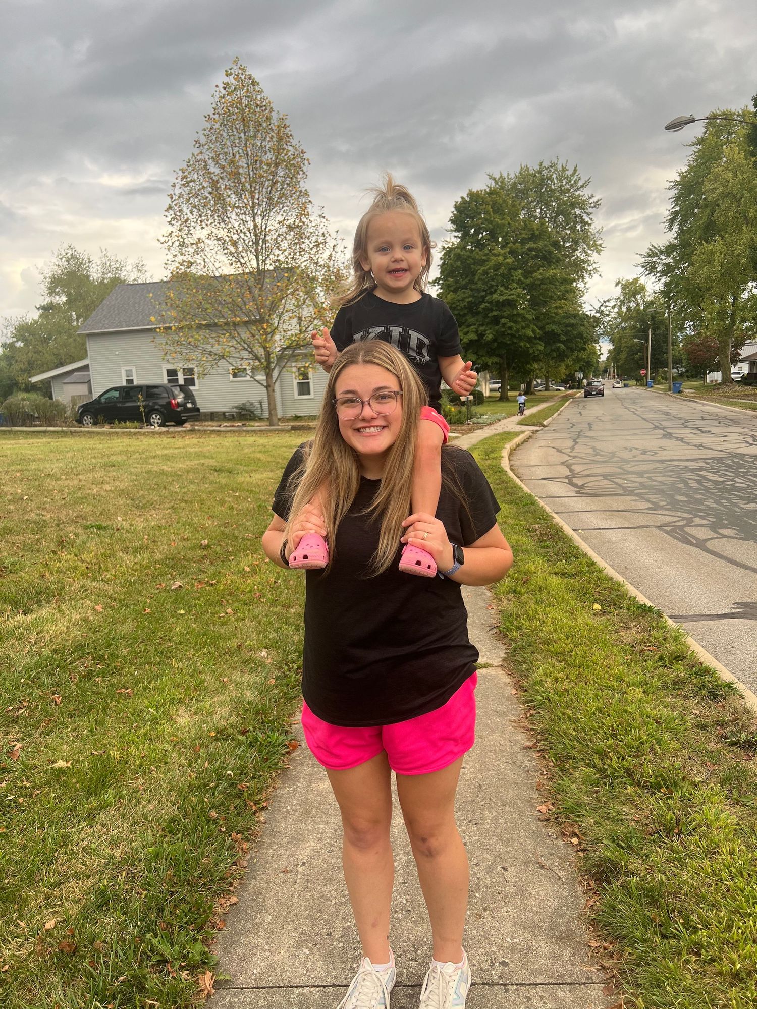 A person exercising outdoors on a paved path with bright pink shorts.