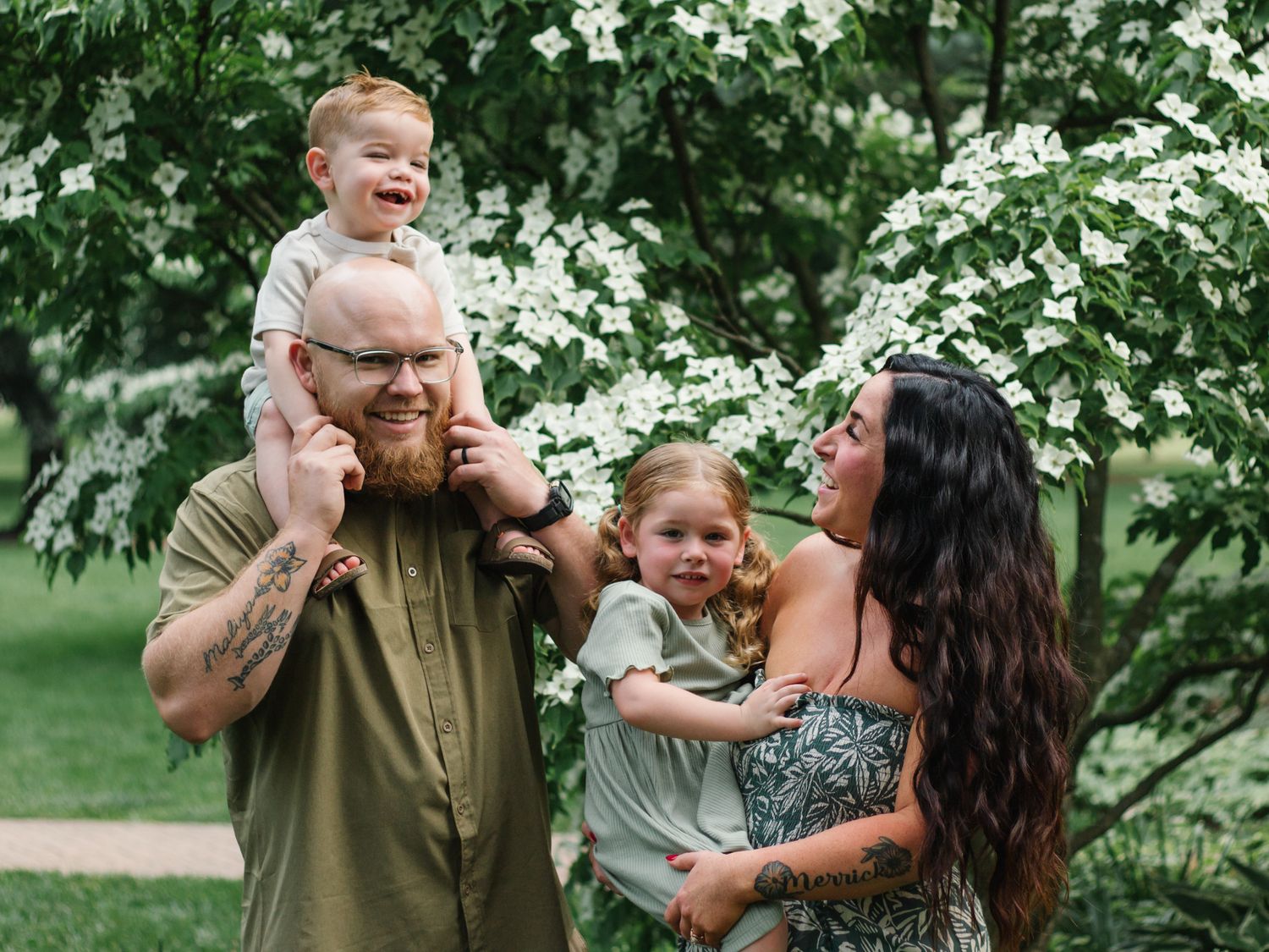 Candid family moments captured in a lush garden setting with white flowers.
