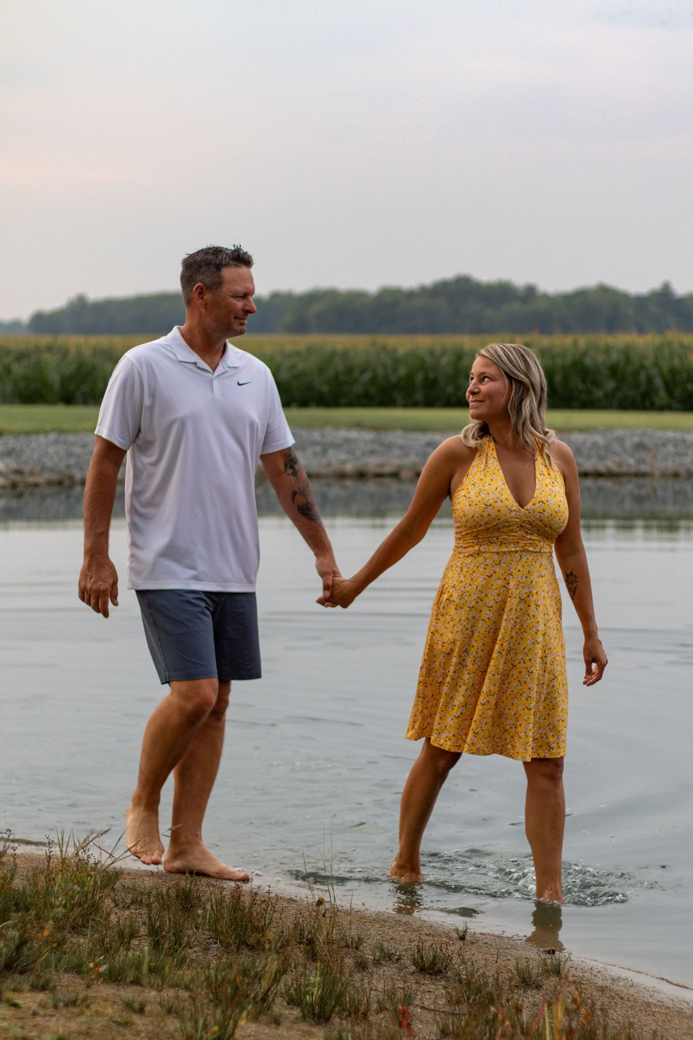 Couple walking and playing along the water's edge at dusk.
