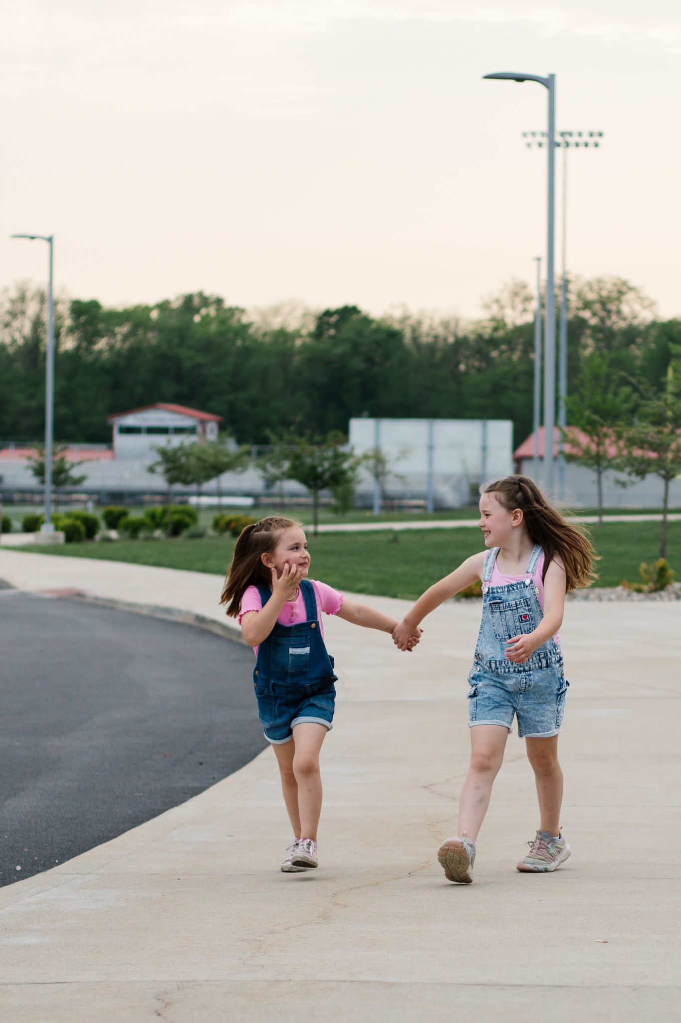 Playful children running and laughing on a concrete path outdoors.