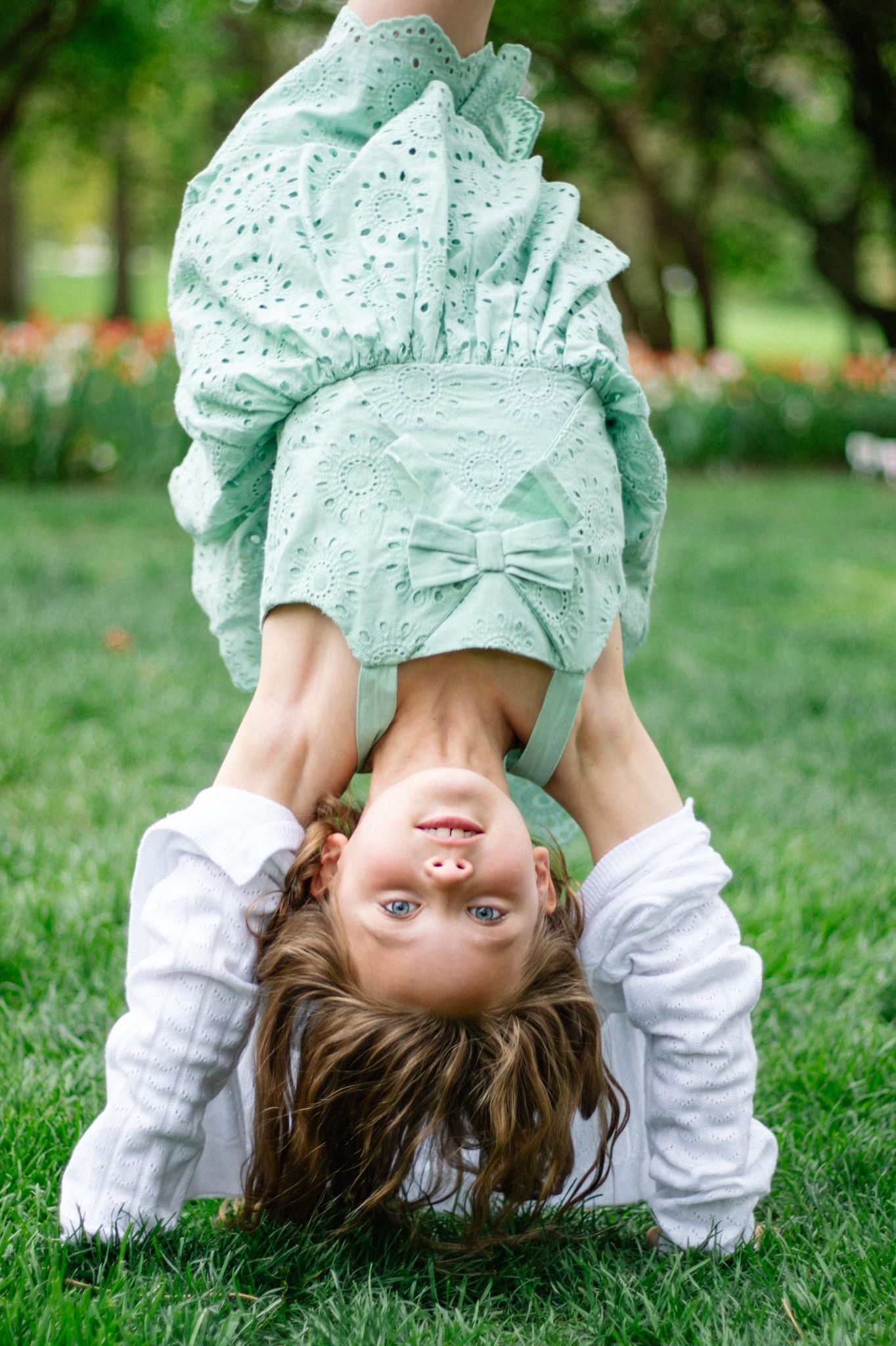 Playful sequence doing handstand on grass in mint green dress.