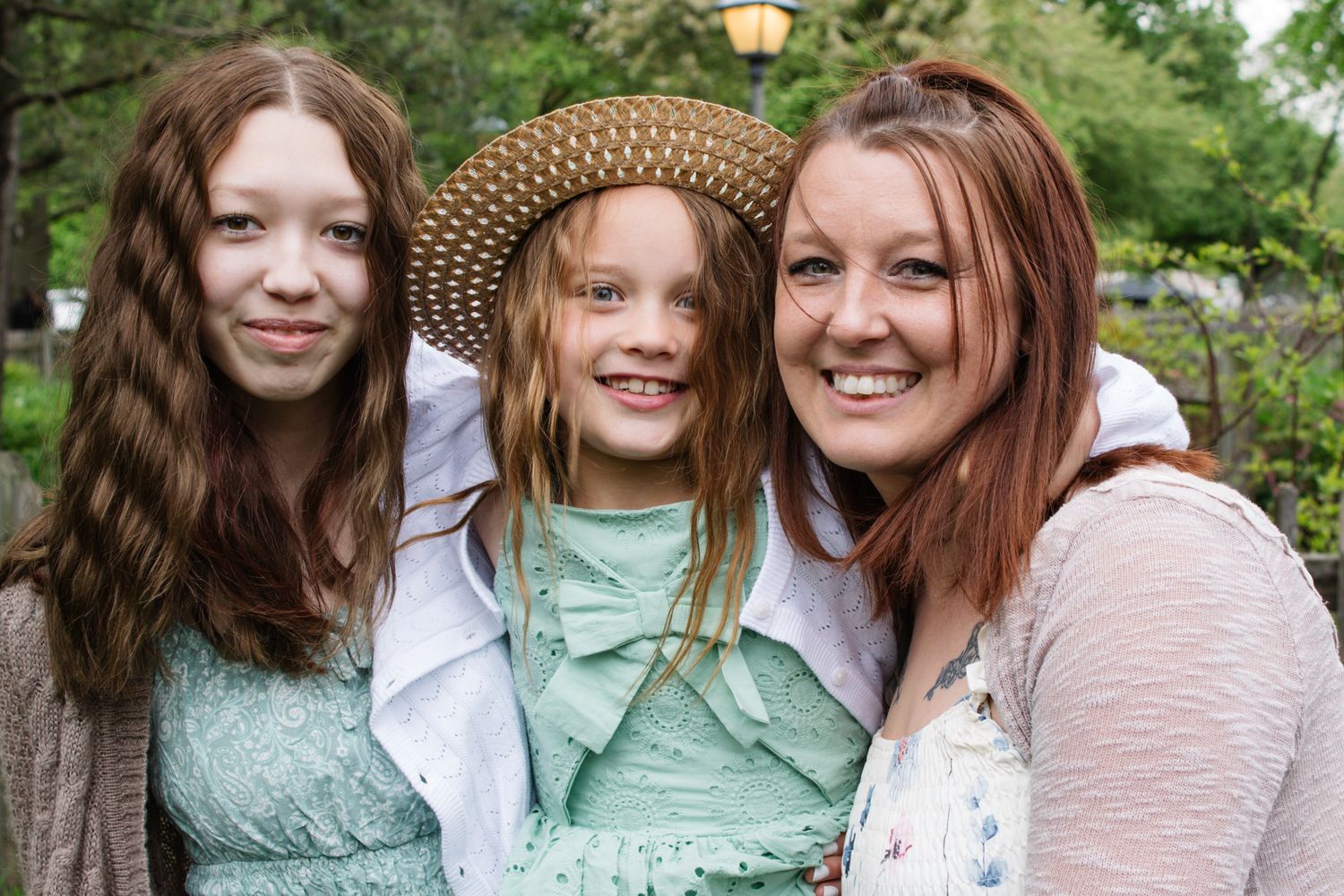 Casual outdoor portrait of family members in coordinating outfits against garden backdrop.