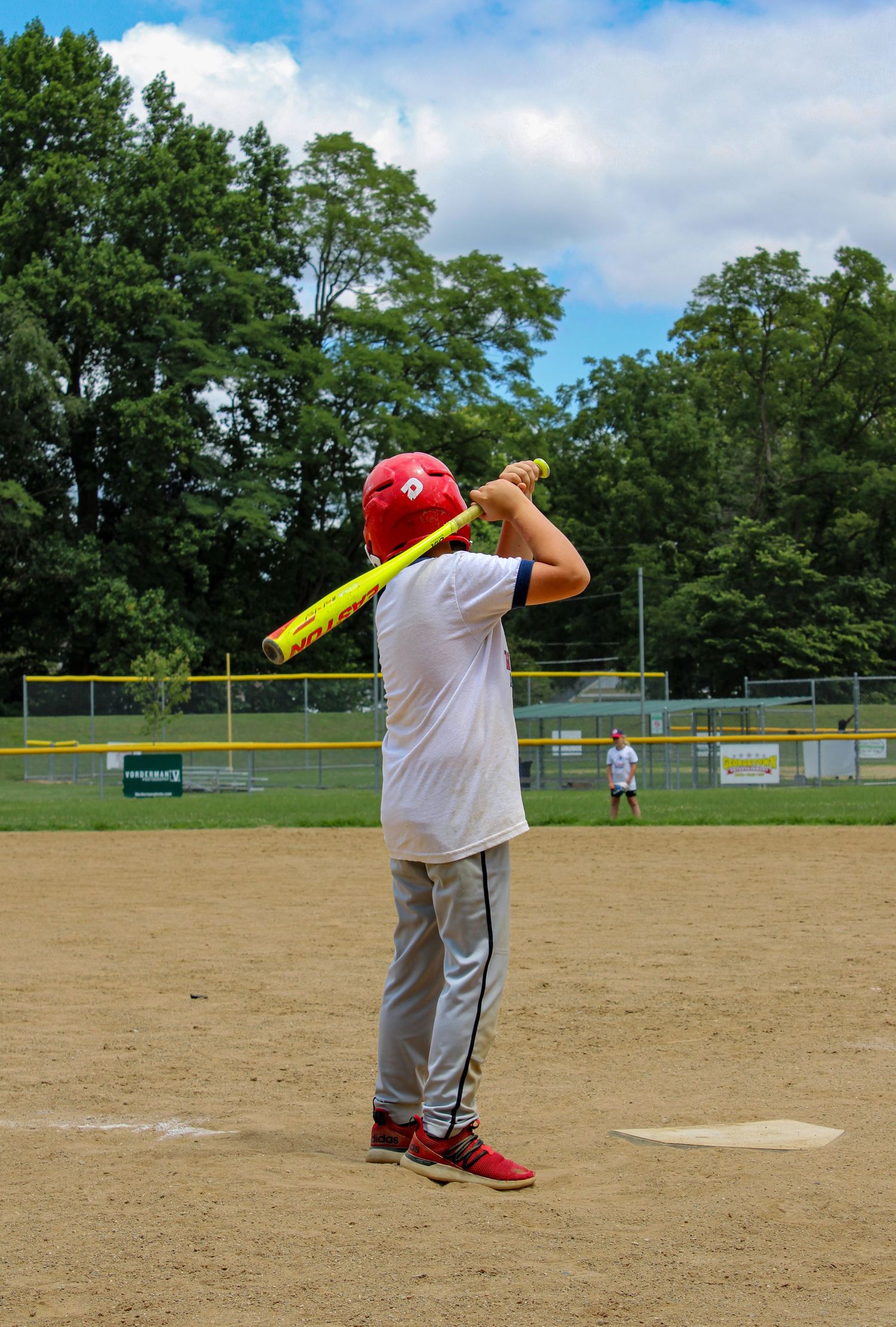 Young baseball player practicing batting stance on a sunny day at the baseball field.