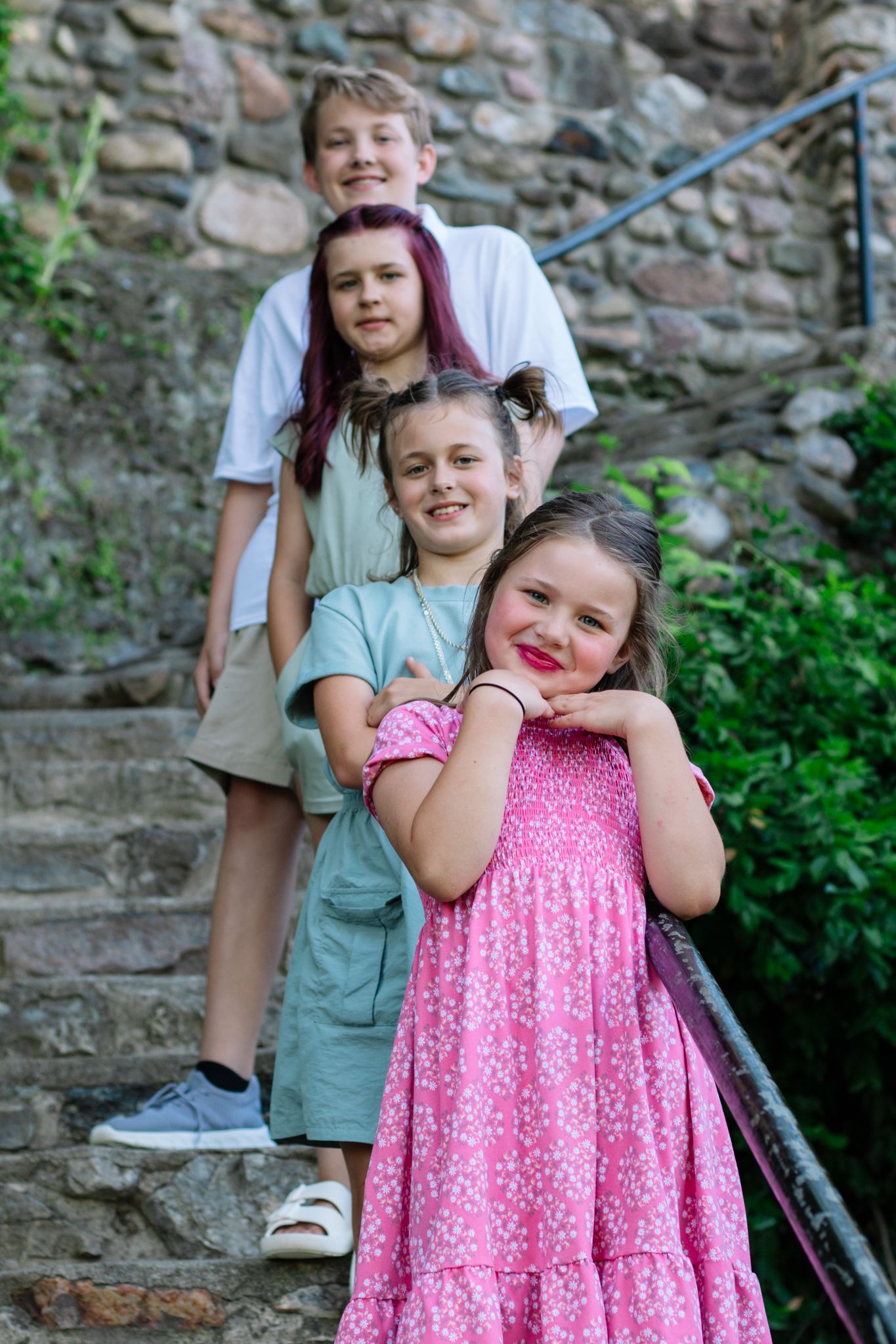 Children posing playfully on stone steps during an outdoor family photo session.