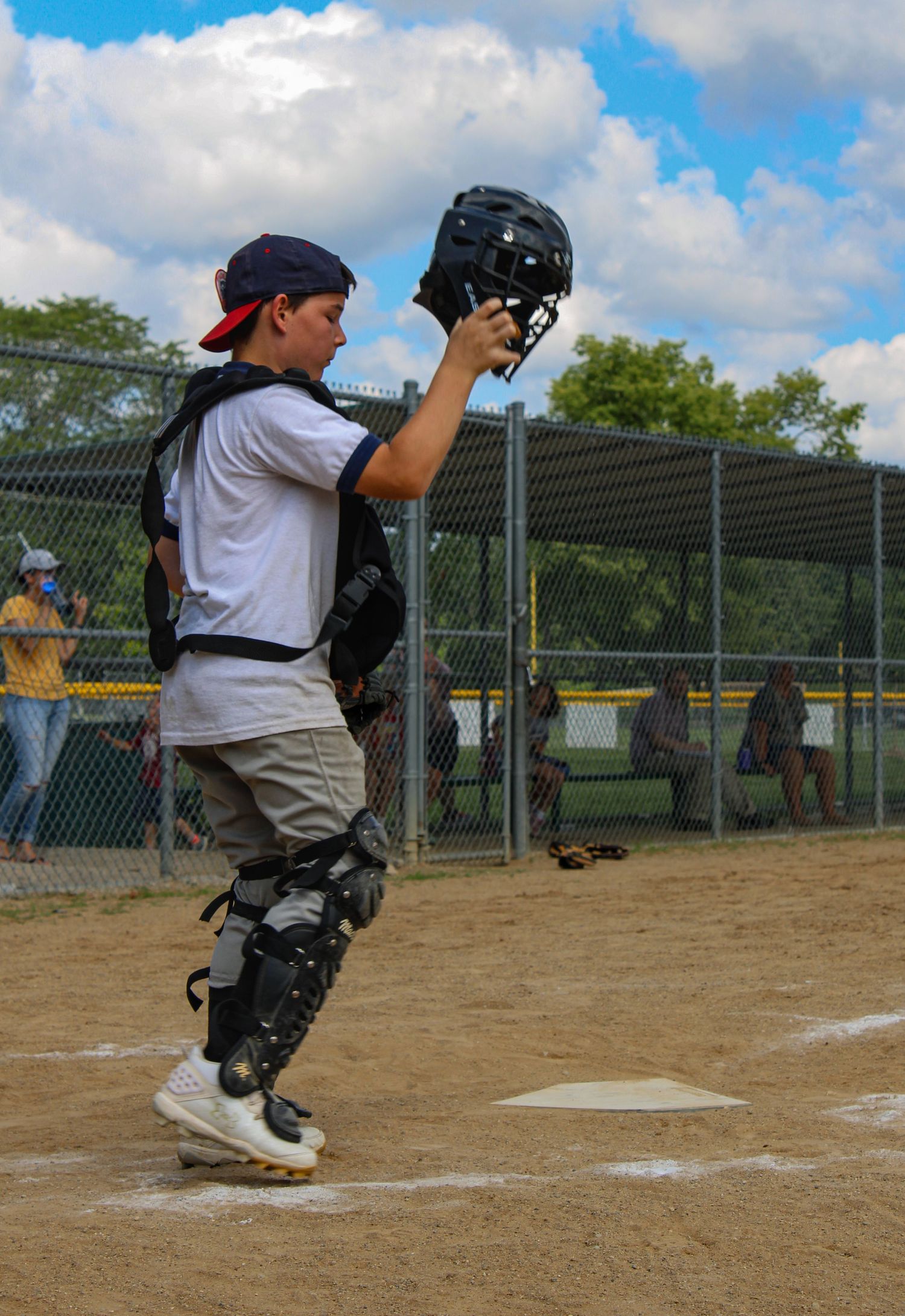 Catcher practicing blocking drills on baseball diamond with protective gear.