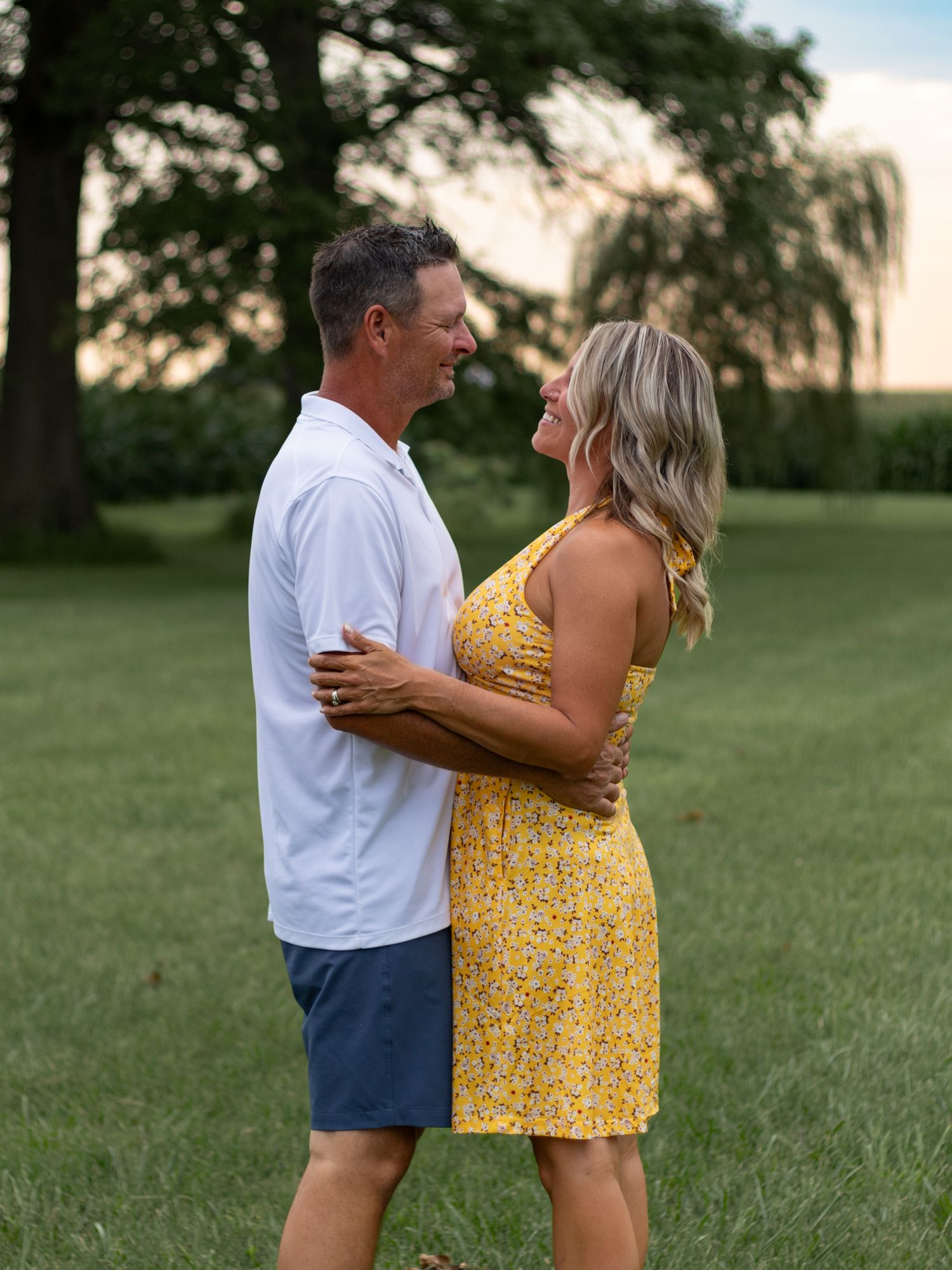 Sequence showing a couple in casual summer attire embracing in a green field.