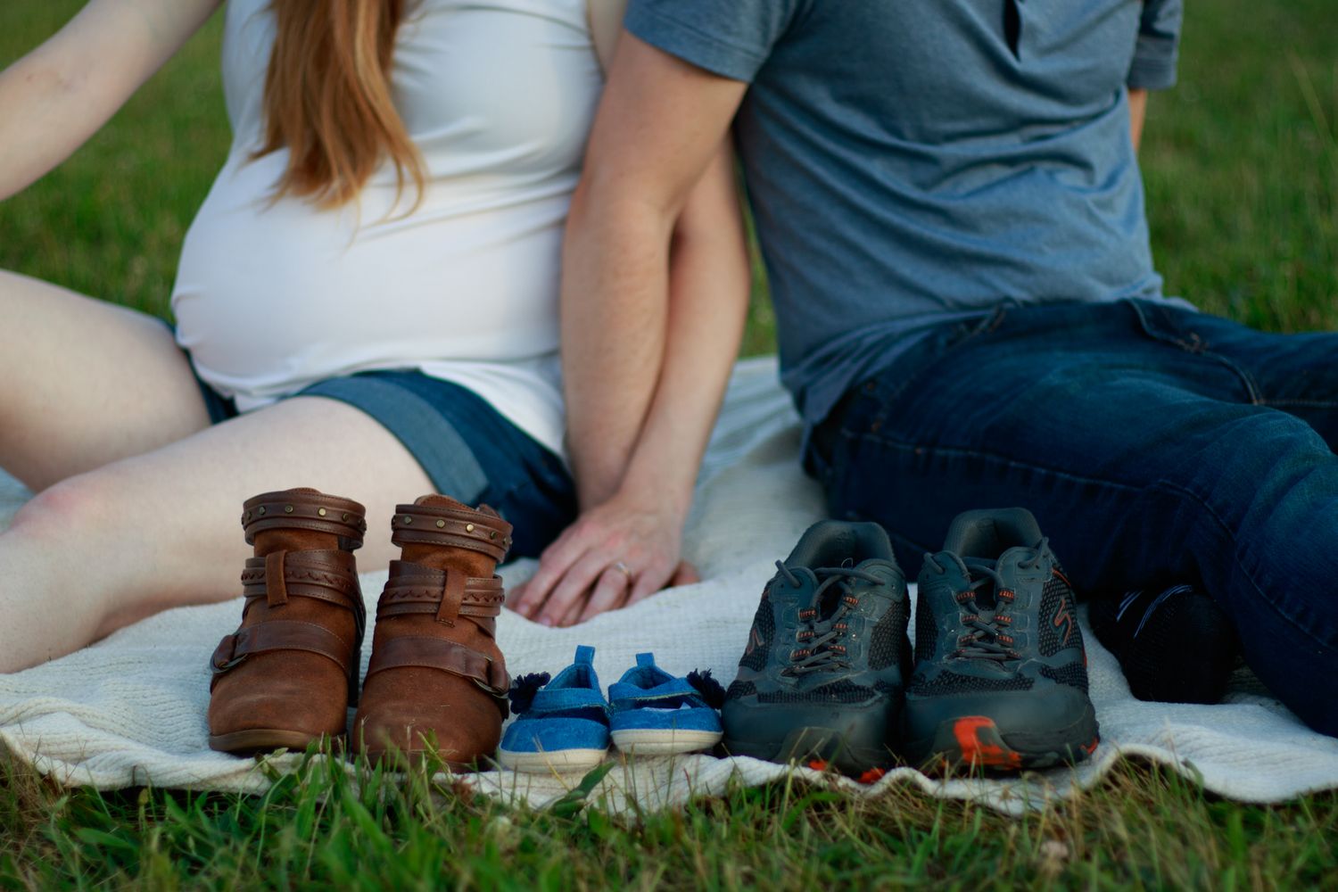 Couple sitting together on blanket during pregnancy photoshoot.