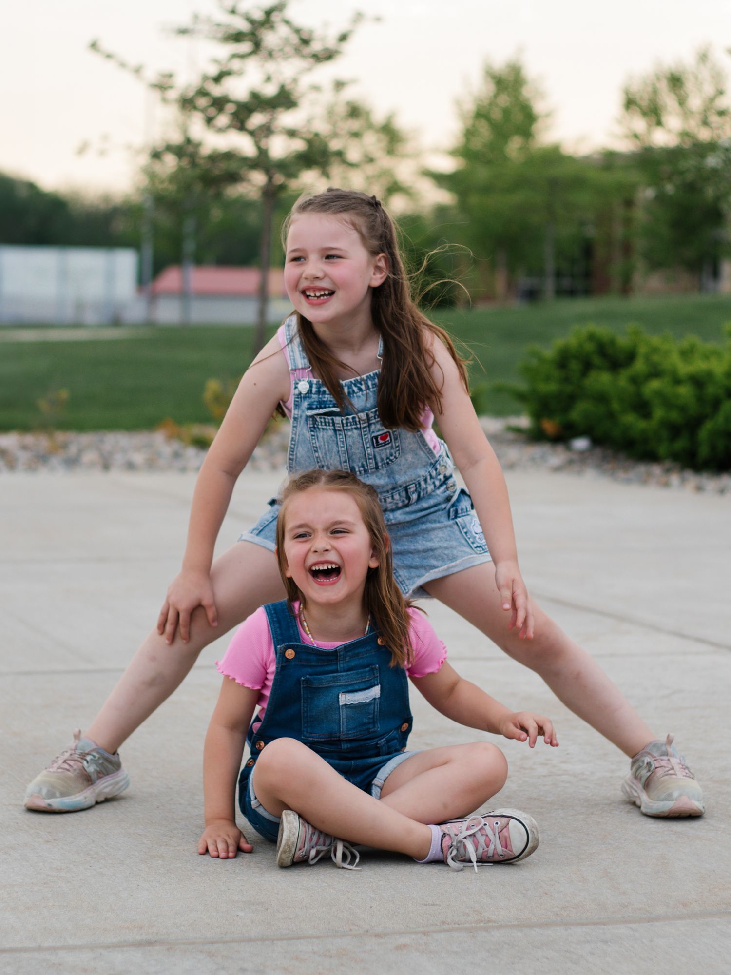 Children in denim outfits playing and laughing together on concrete.