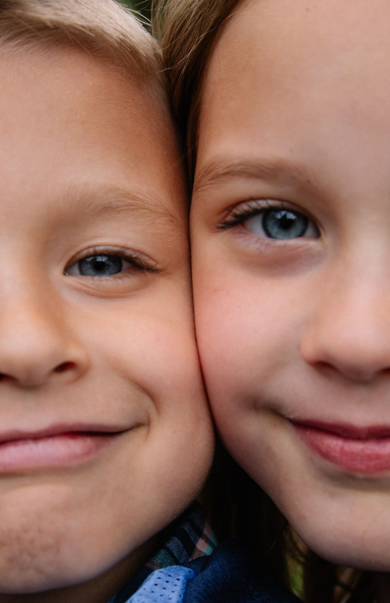 Close up portrait of two young children's faces sharing a joyful moment.