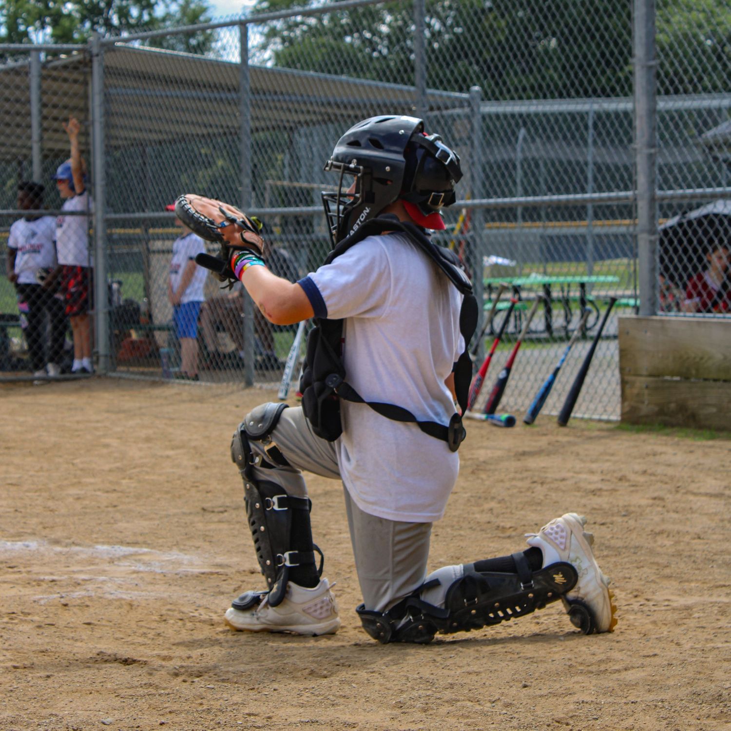 Baseball catcher practicing defensive moves on dirt infield during training.