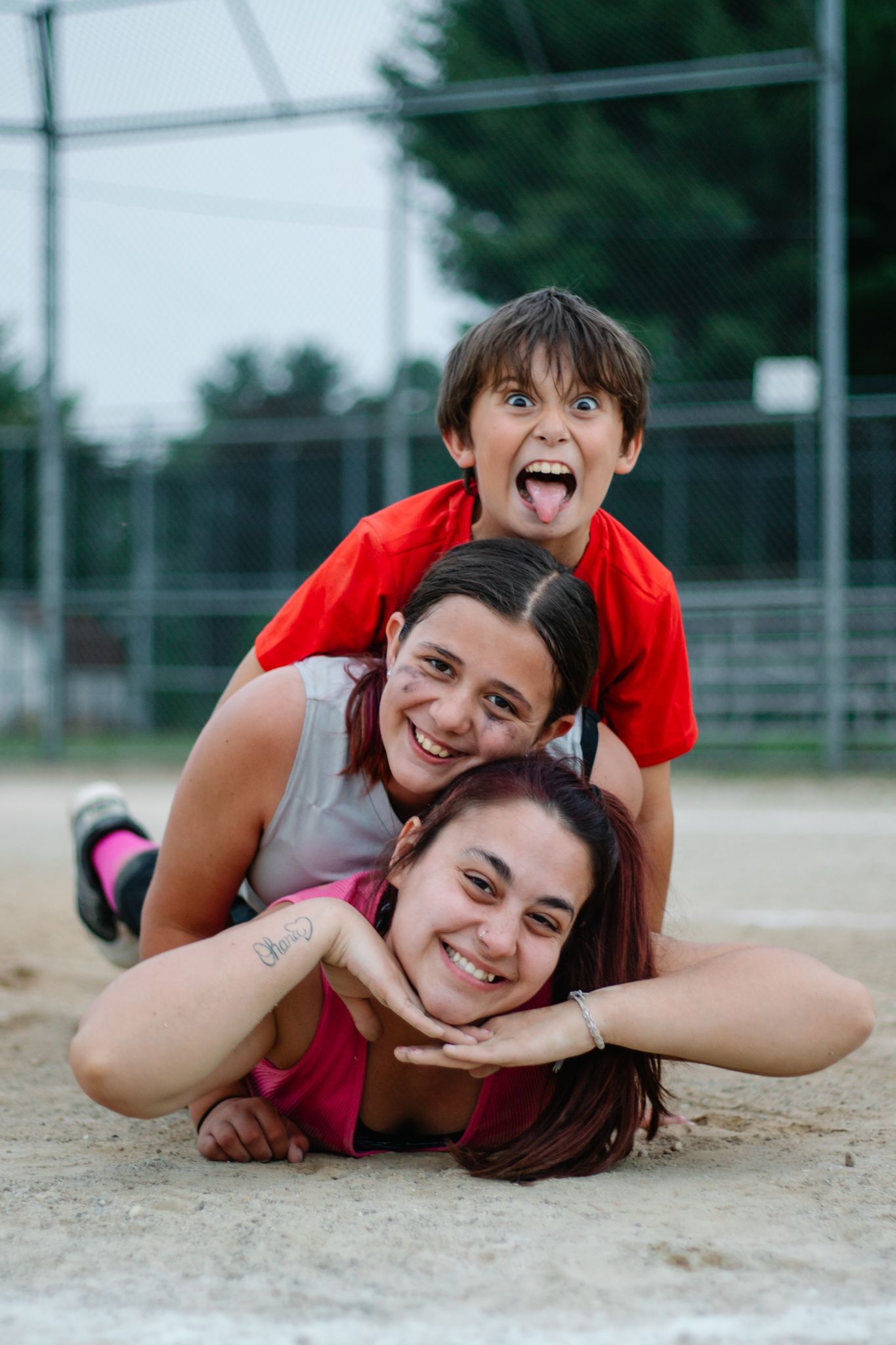 Two people having fun while posing on baseball diamond sand.