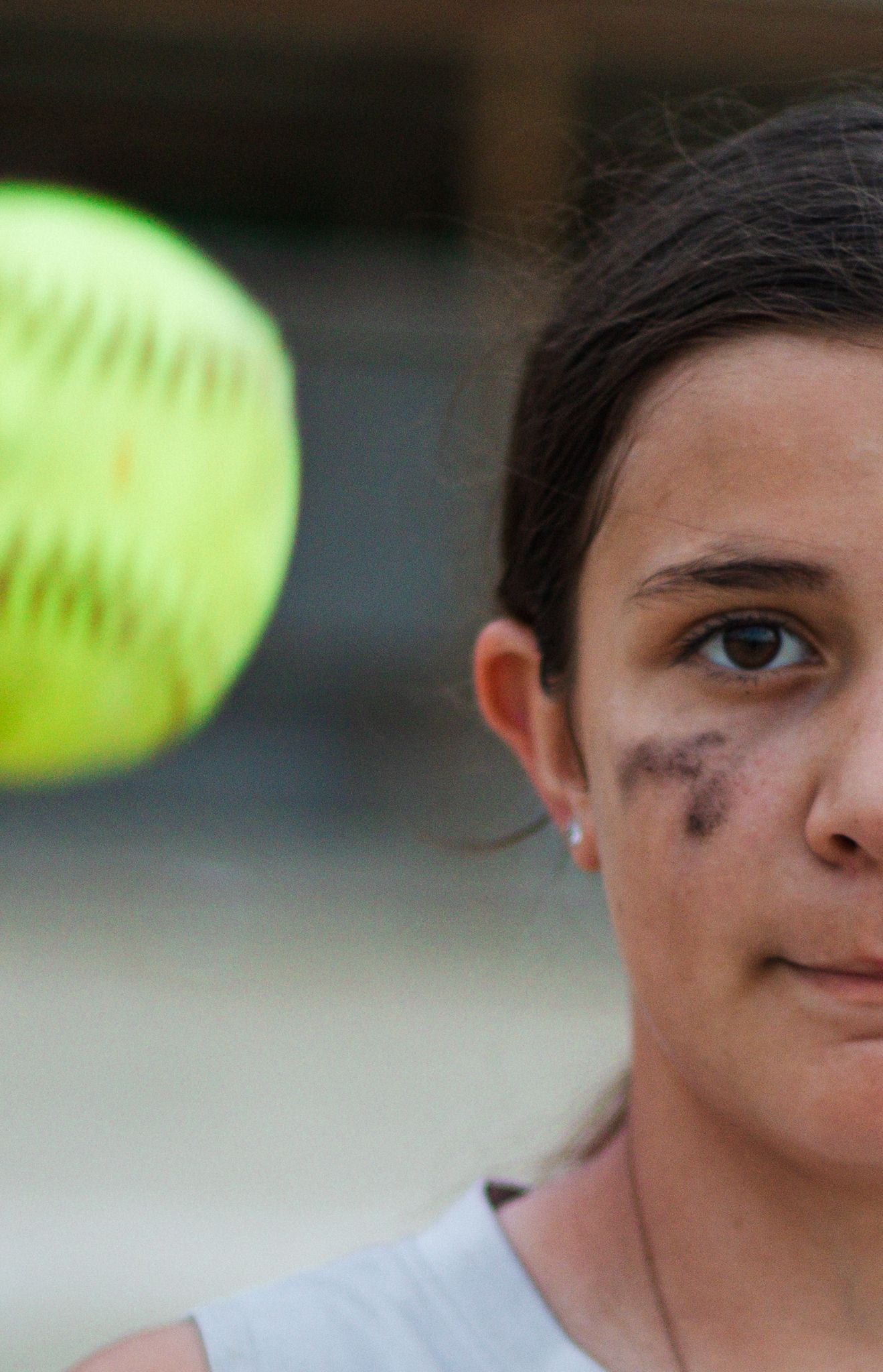 Close-up shot of softball player with yellow ball in motion.