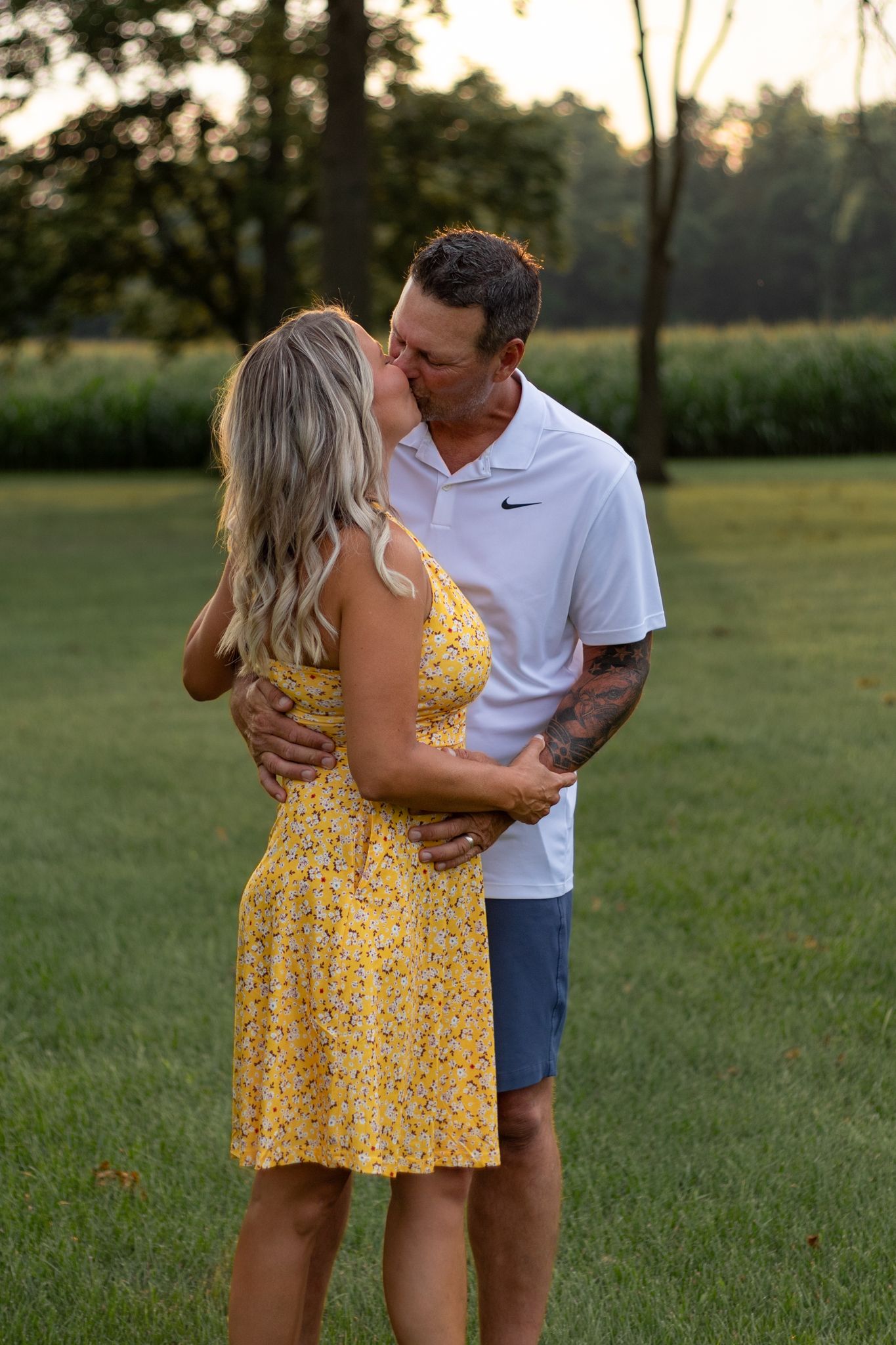 Romantic couple embracing in a grassy field during sunset.