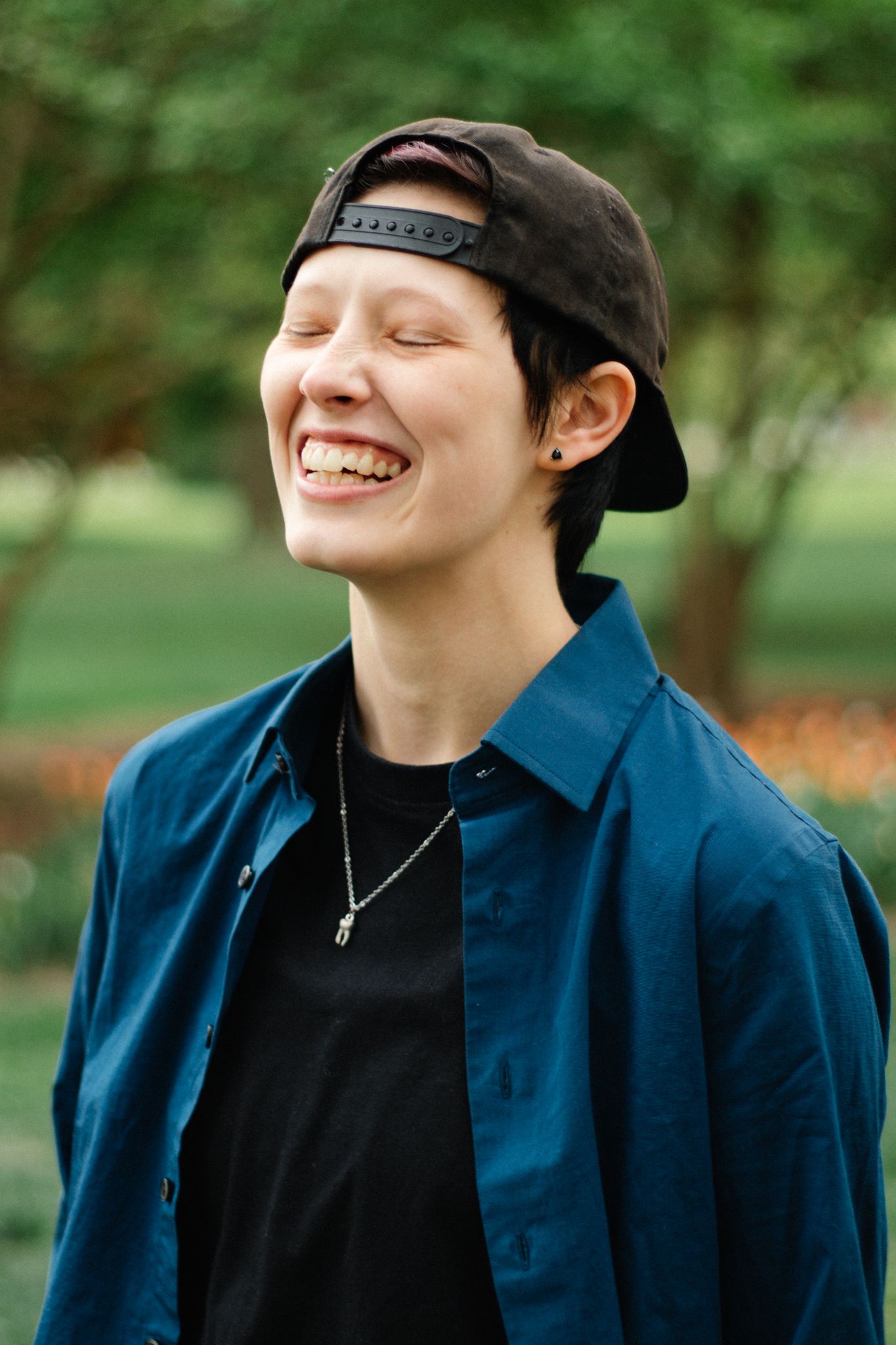 Progressive shots of someone in a dark blue jacket and black cap laughing outdoors.