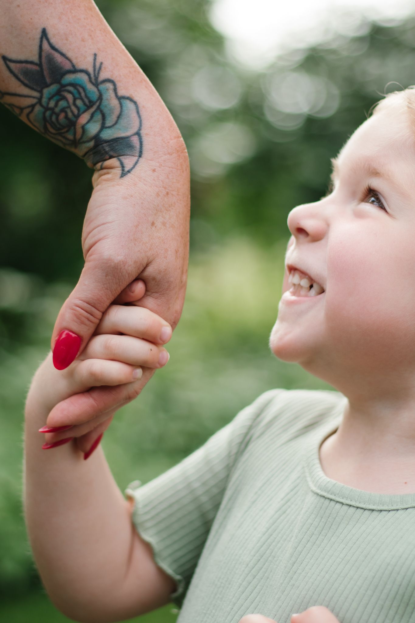 Sweet moment captured as child kisses hand with blue floral tattoo.