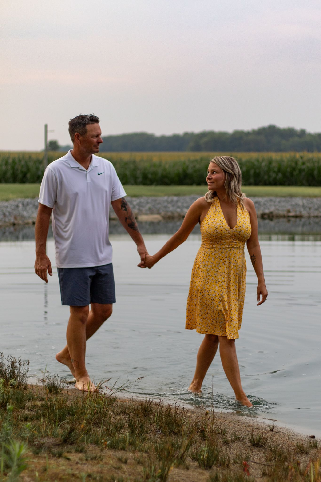 Playful couple walking along the shoreline at sunset.
