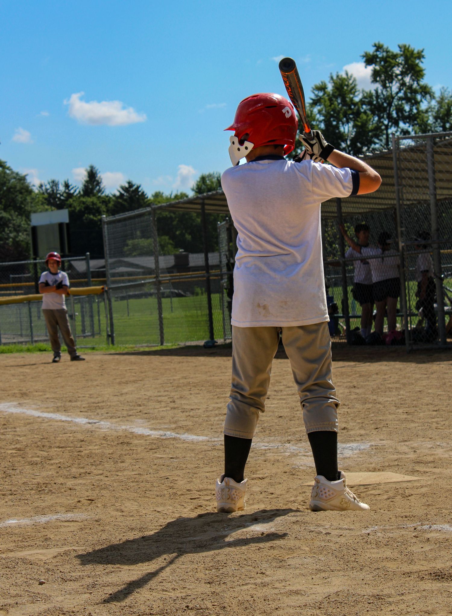 Baseball players practicing on dusty diamond field during summer day.