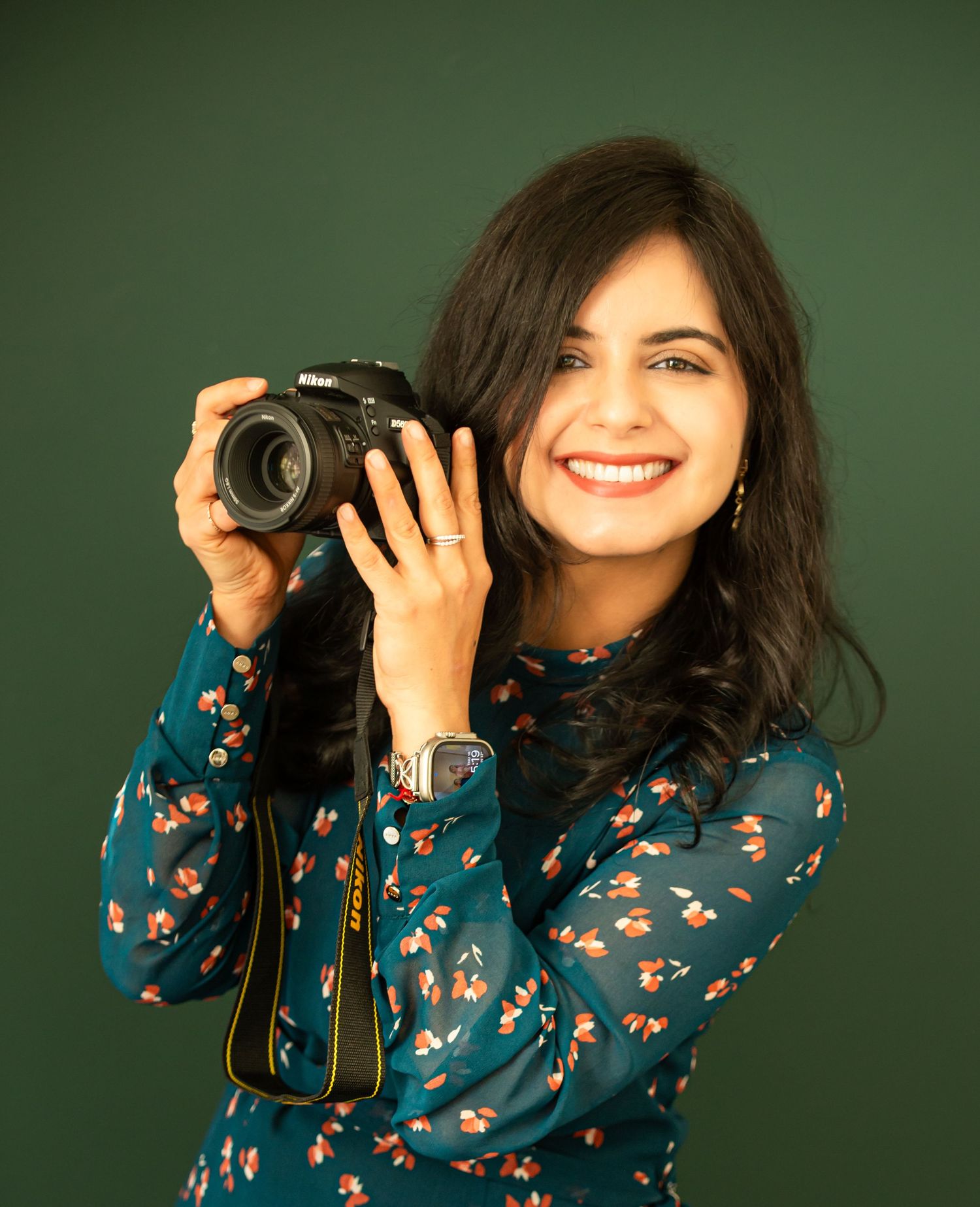 Photographer Ekta Khatri posing with a camera during a studio happy hour event in Northern Virginia