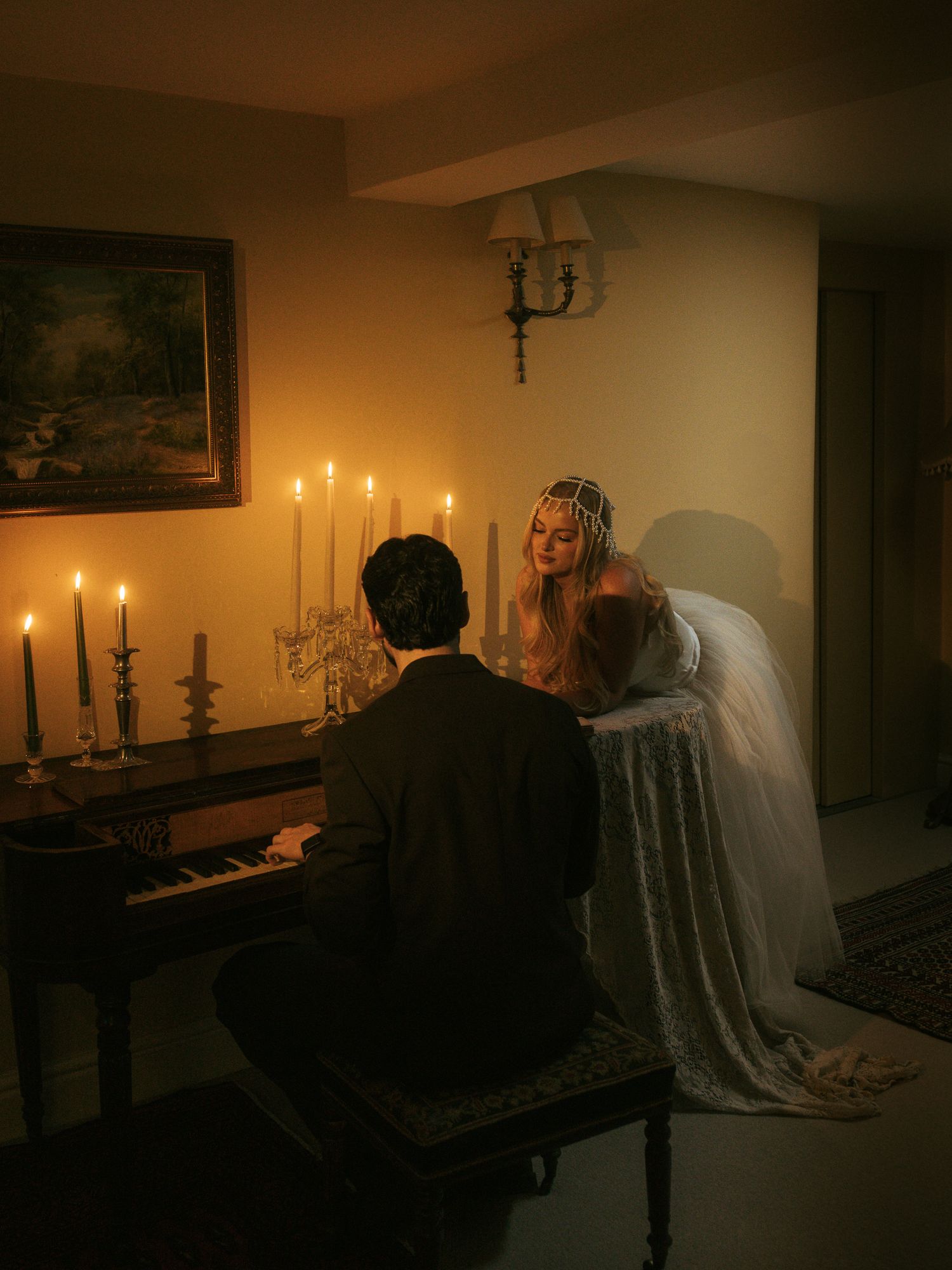 A haunting candlelit scene shows figures in a dimly lit room with vintage furnishings and candelabras creating dramatic shadows.