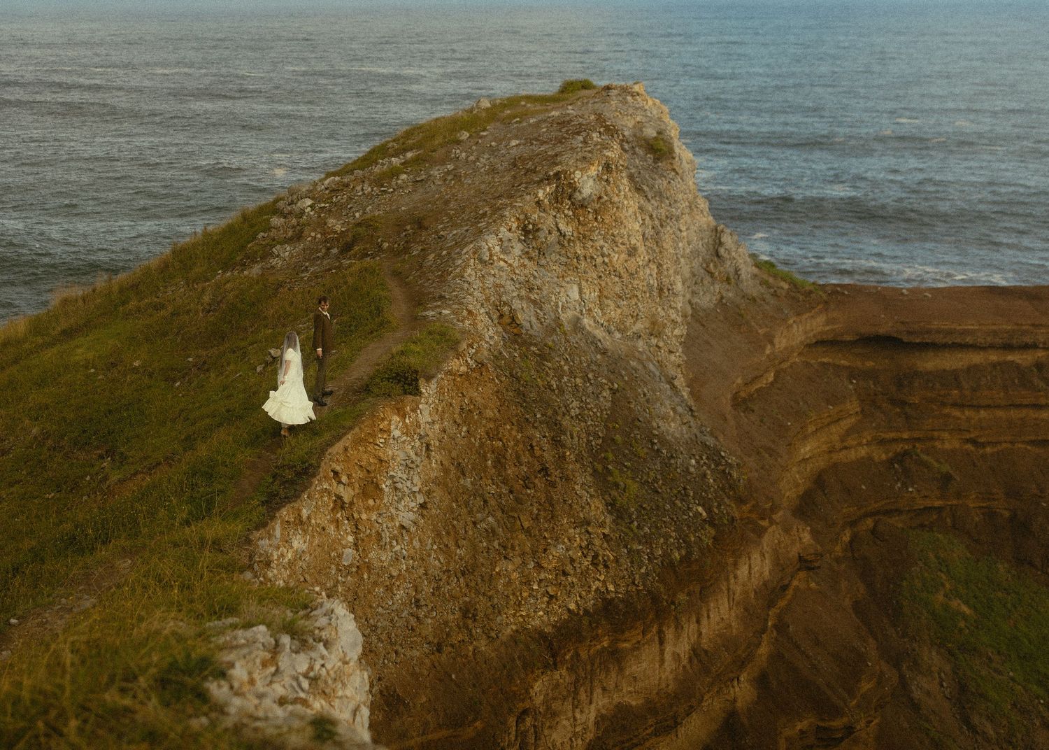 A series of rugged coastal cliffs overlooking the ocean during sunset with dramatic lighting and natural formations.