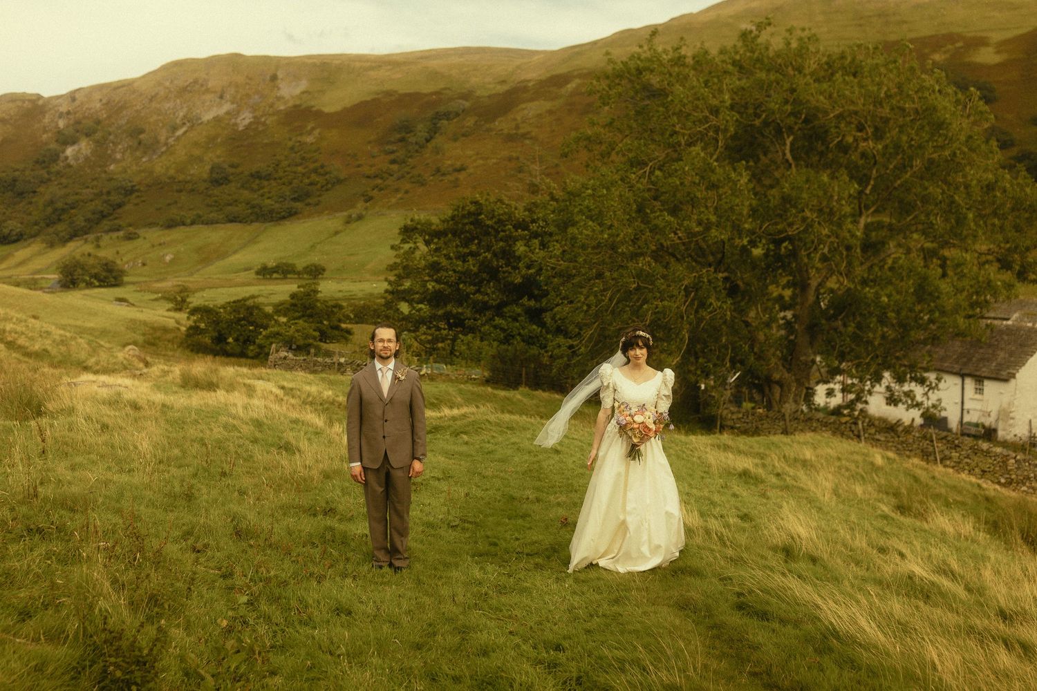 A couple walks through rolling green hills in Scotland during their wedding photo session at sunset.
