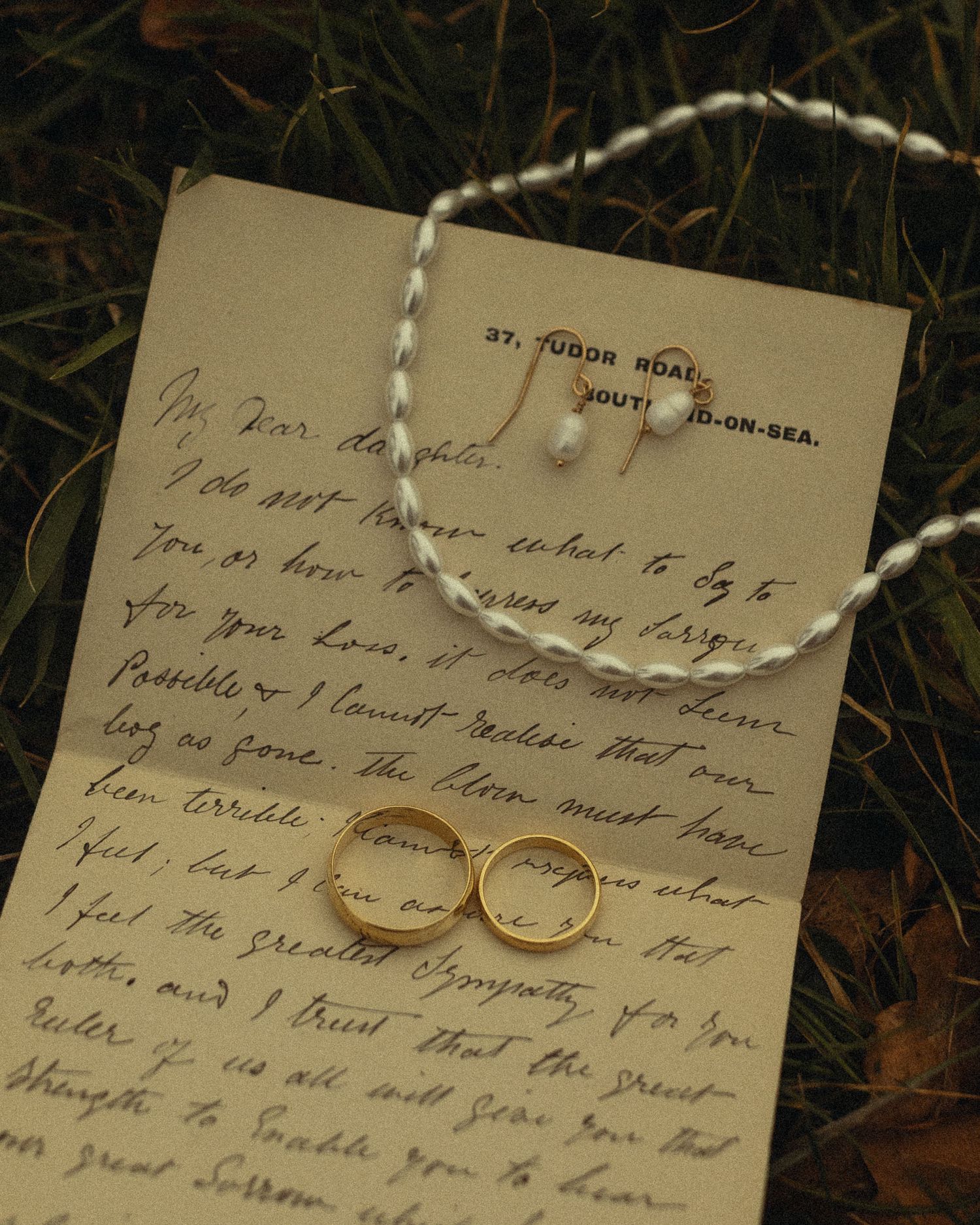 Vintage handwritten letters and wedding rings displayed on a dark surface create a romantic composition.