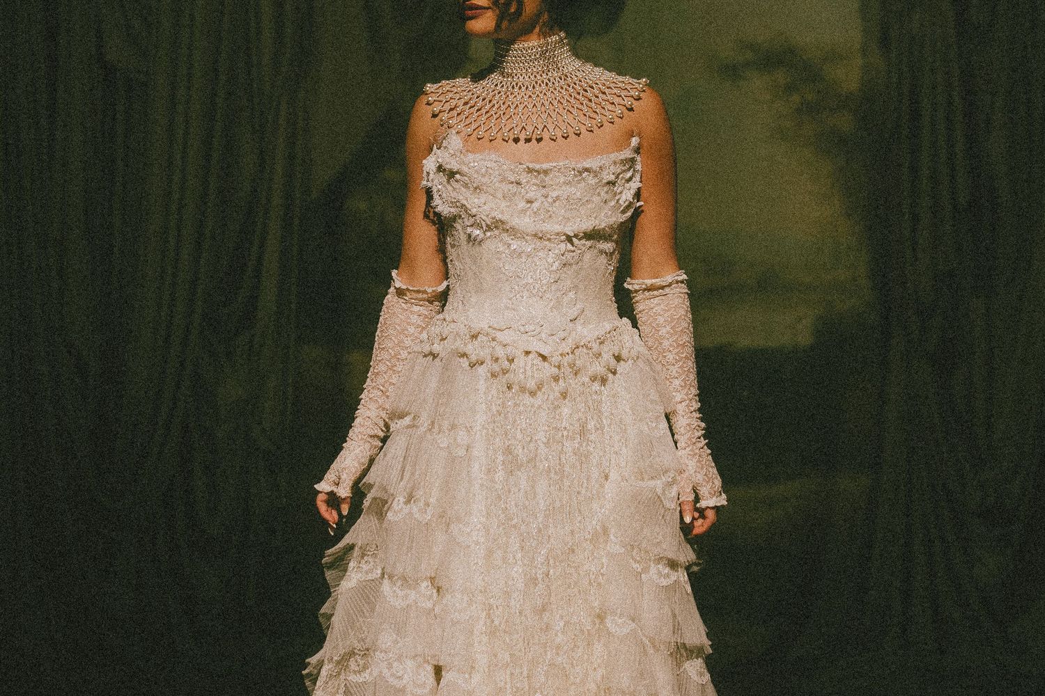 A collection of vintage white lace wedding dresses displayed on mannequins in a dimly lit room.