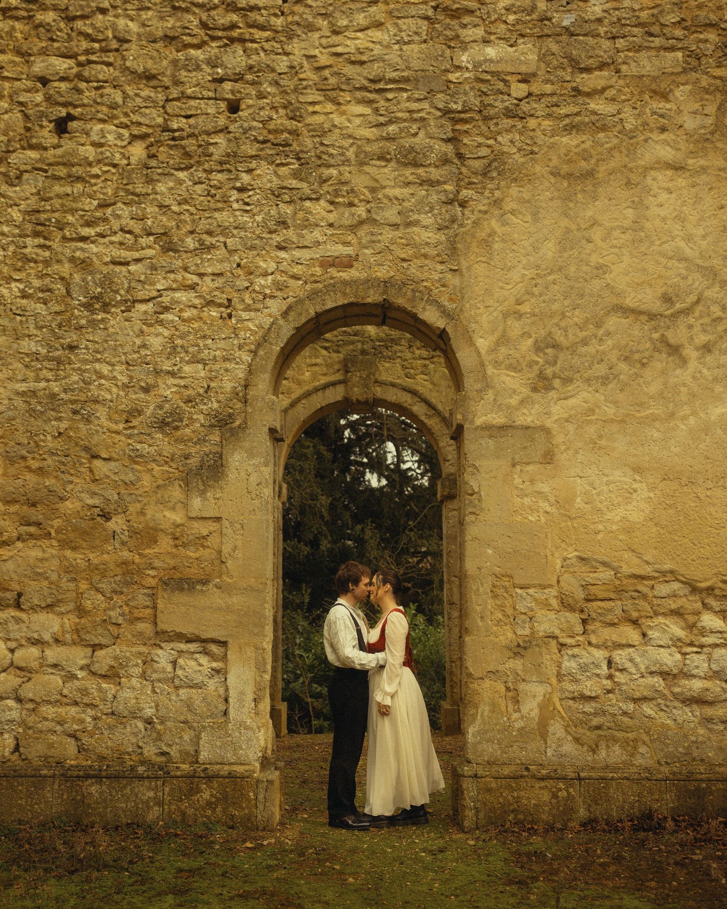 A sequence of stone archways and walls at an old castle or fortress with people standing in various archways.