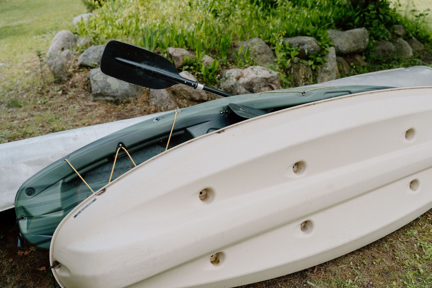 White canoes rest on the grassy shore of a lake.