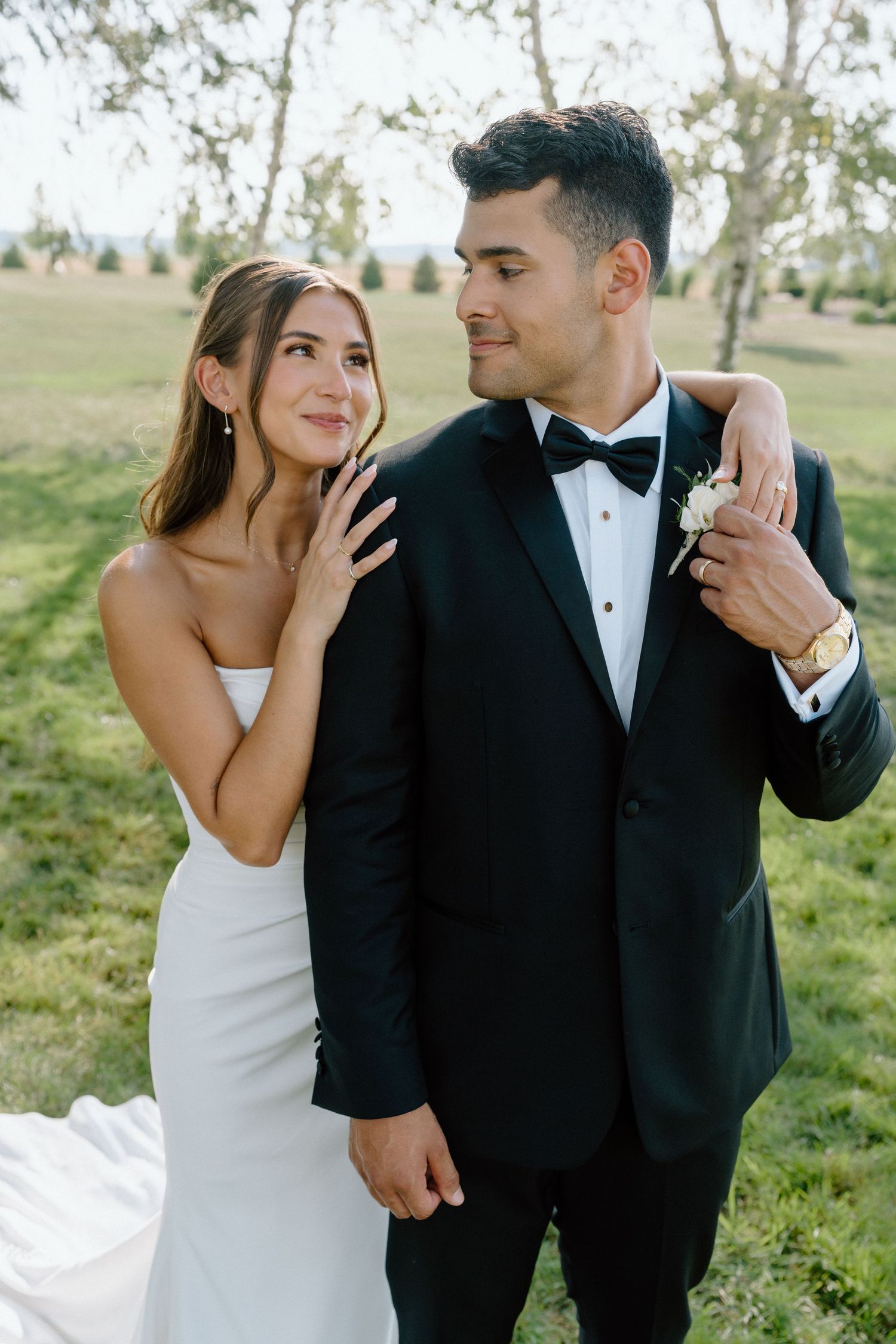 Elegant outdoor wedding portraits showcase a couple in classic black and white attire sharing intimate glances.
