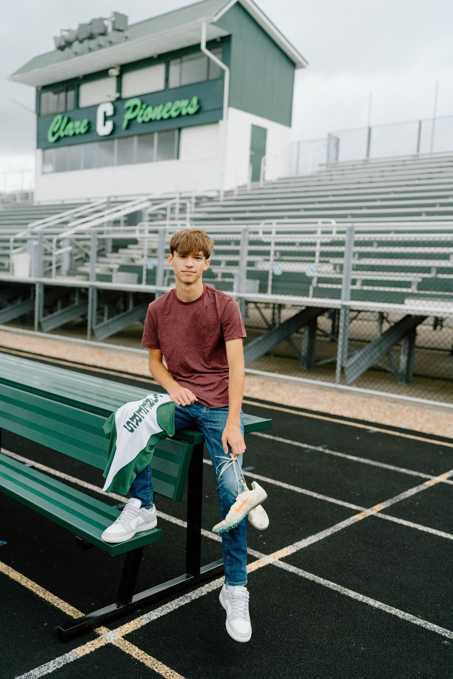 Person sits casually on bleachers at a sports stadium with green and white paint.
