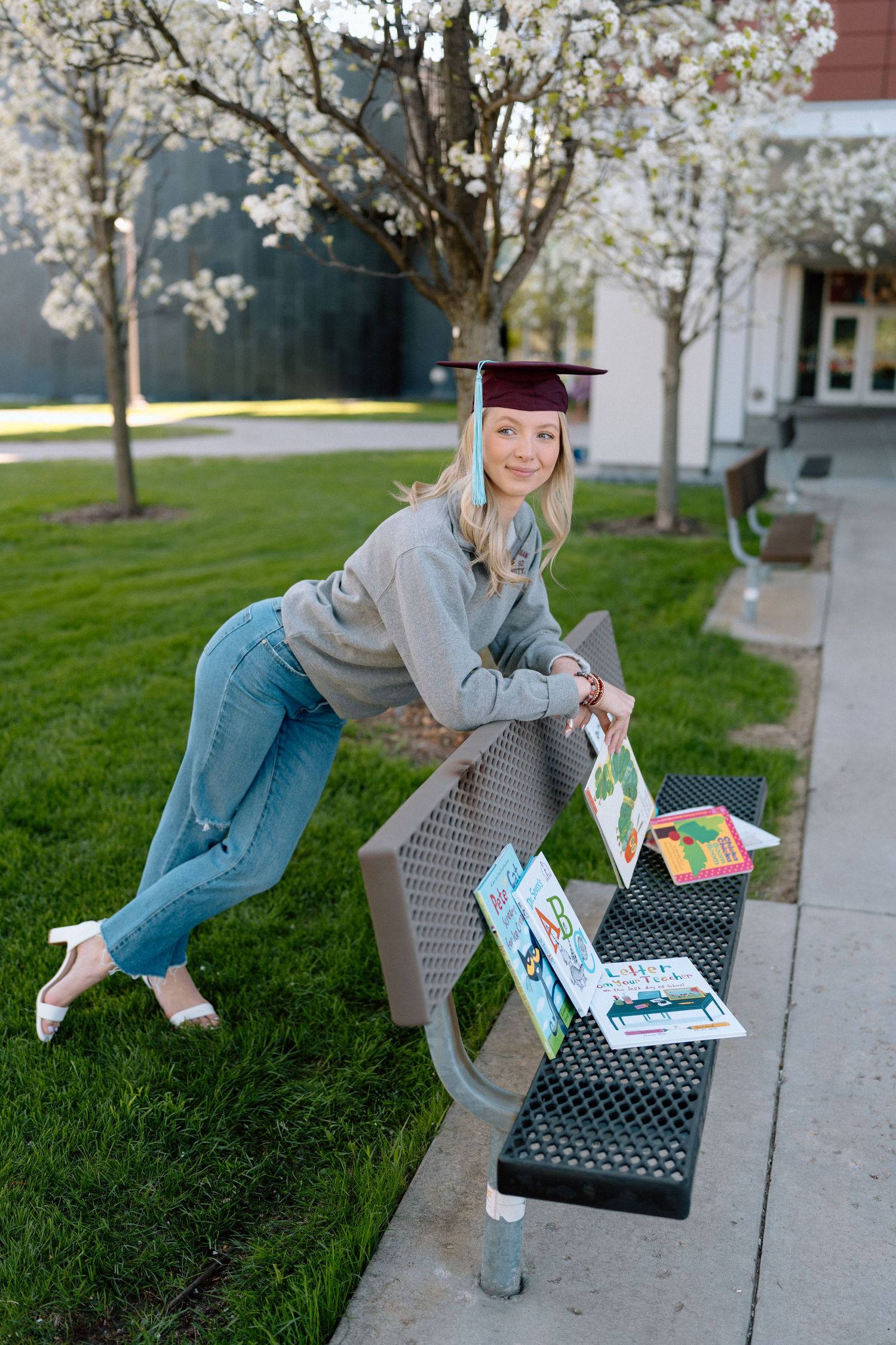 Graduate sits on bench with colorful cards in celebratory photo session.