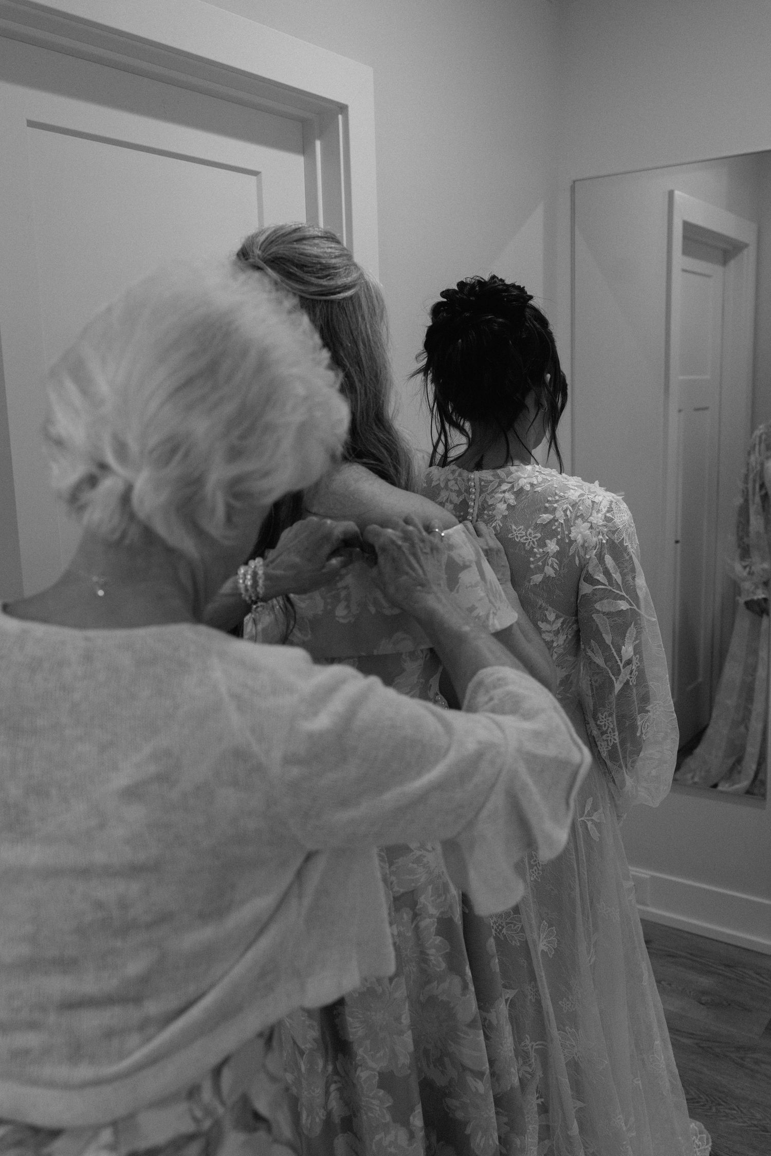 Behind-the-scenes wedding preparation showing dress details in white interior space.