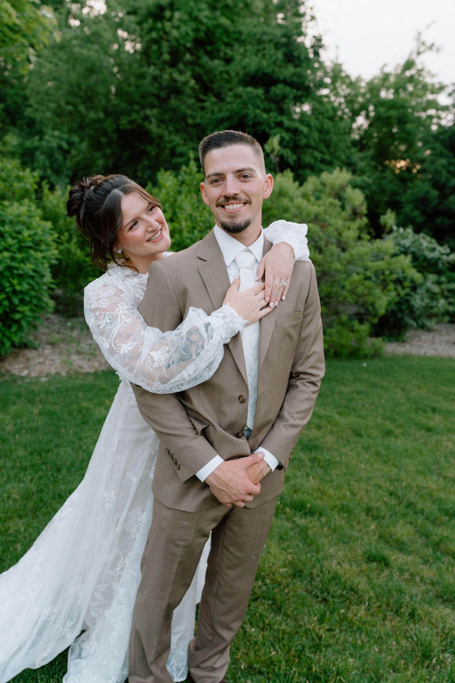Wedding couple shares playful moments on a grassy lawn in vintage-inspired attire.