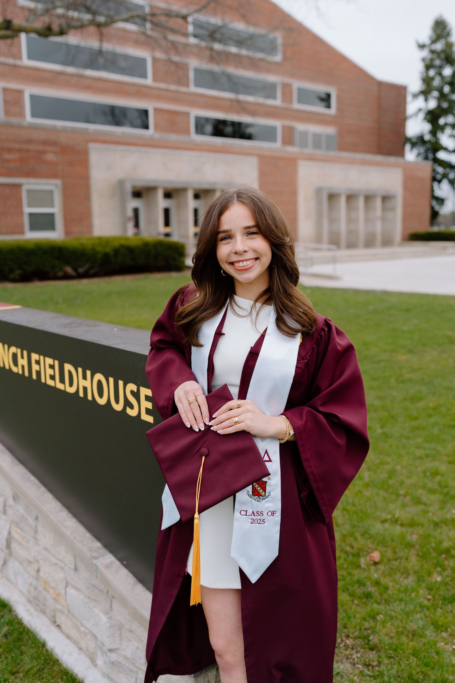 Graduation photos on campus showing maroon academic regalia against brick building backdrop.